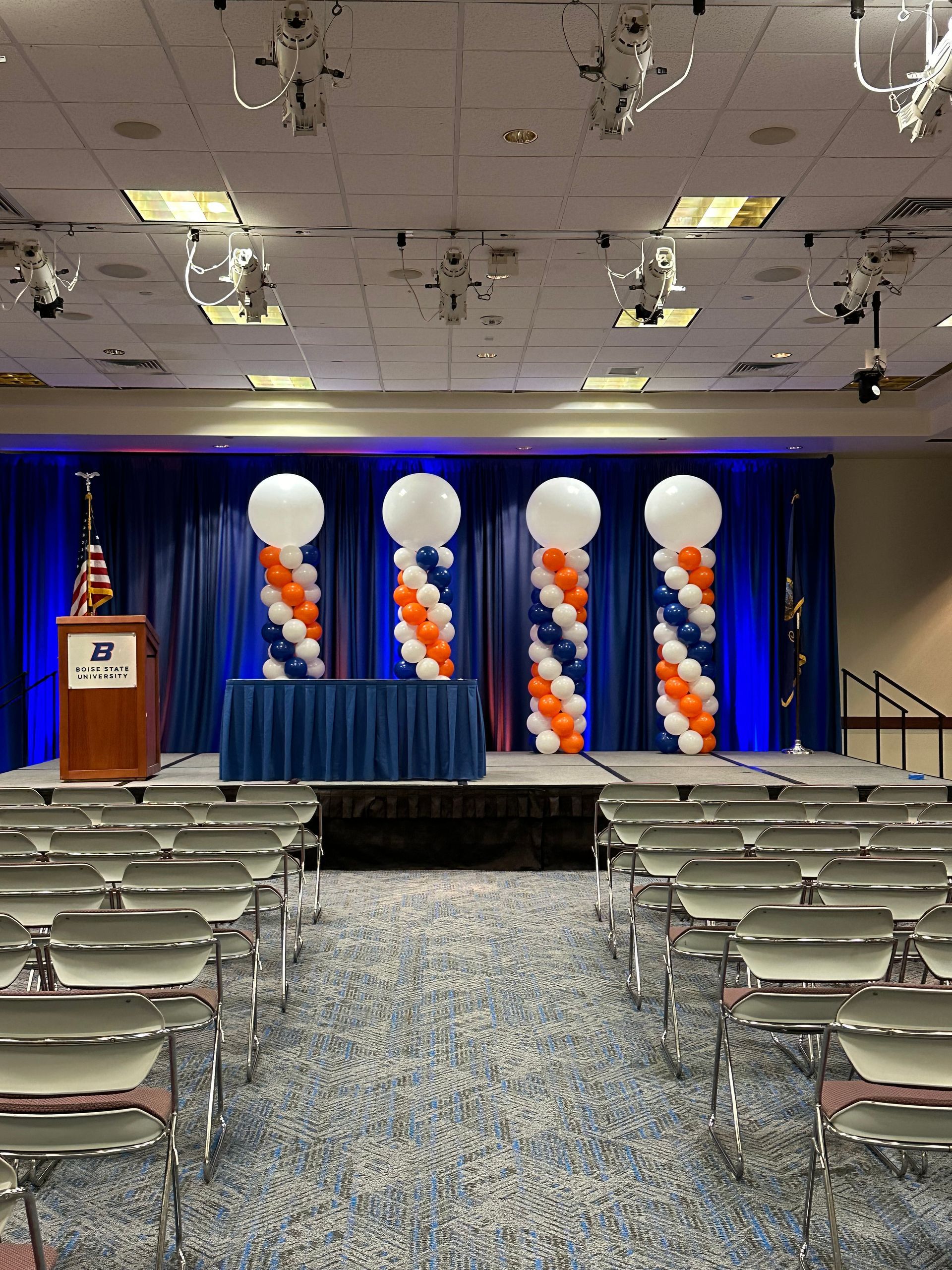 A large room with rows of chairs and balloons on the wall.