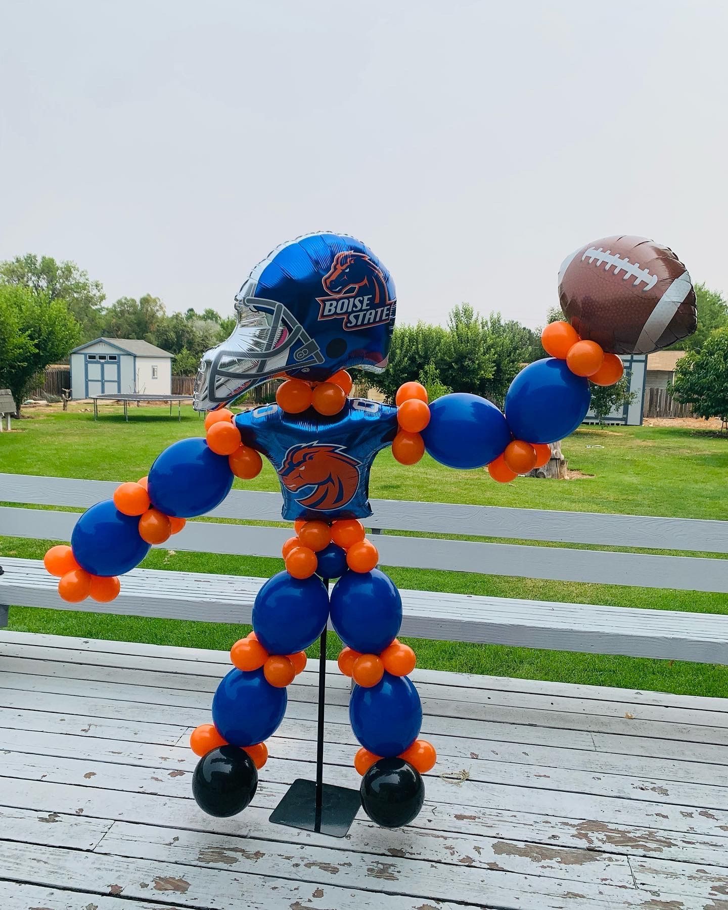 A football player made out of balloons is holding a football.