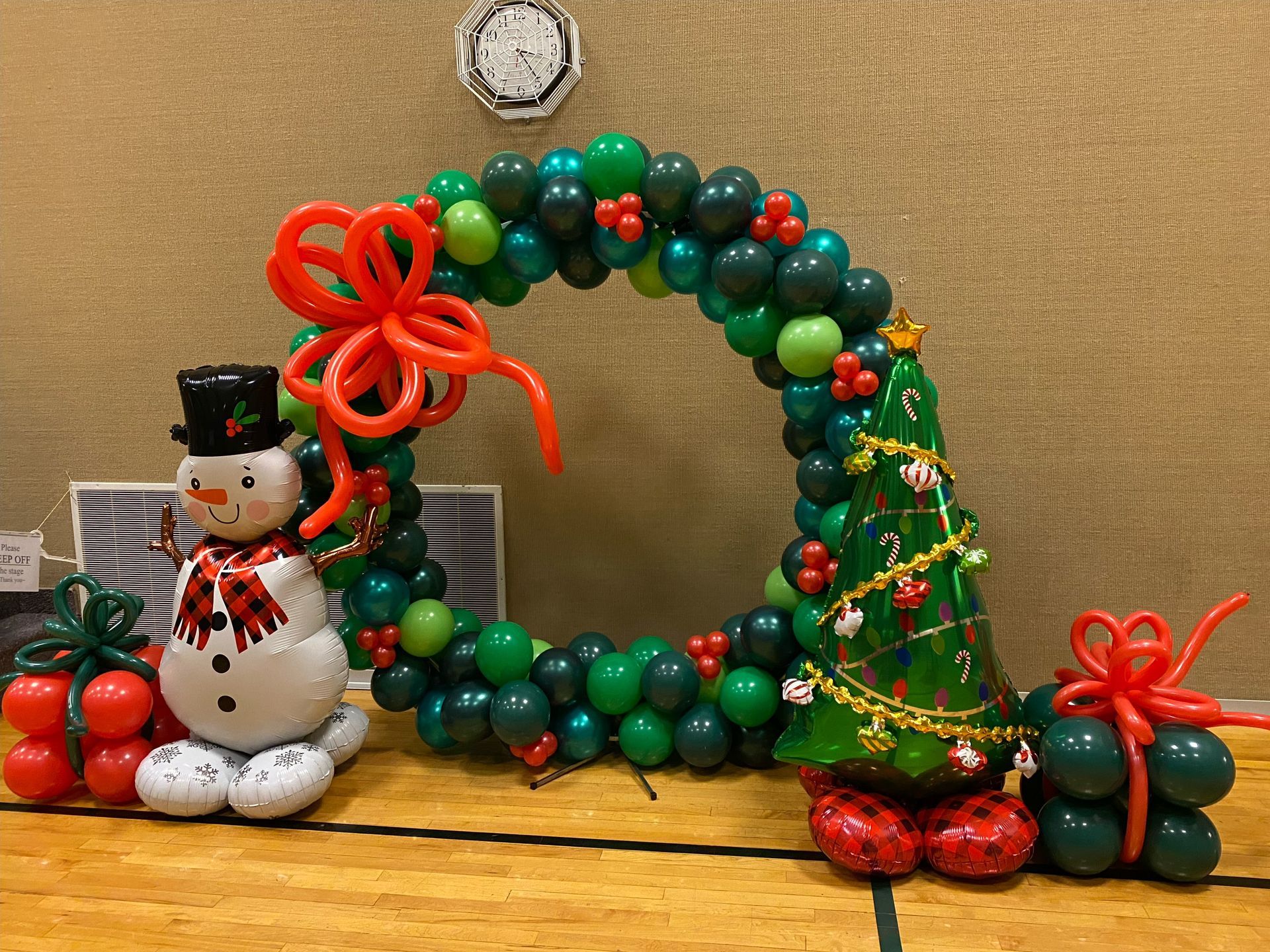 A christmas wreath made of balloons with a snowman and a christmas tree.