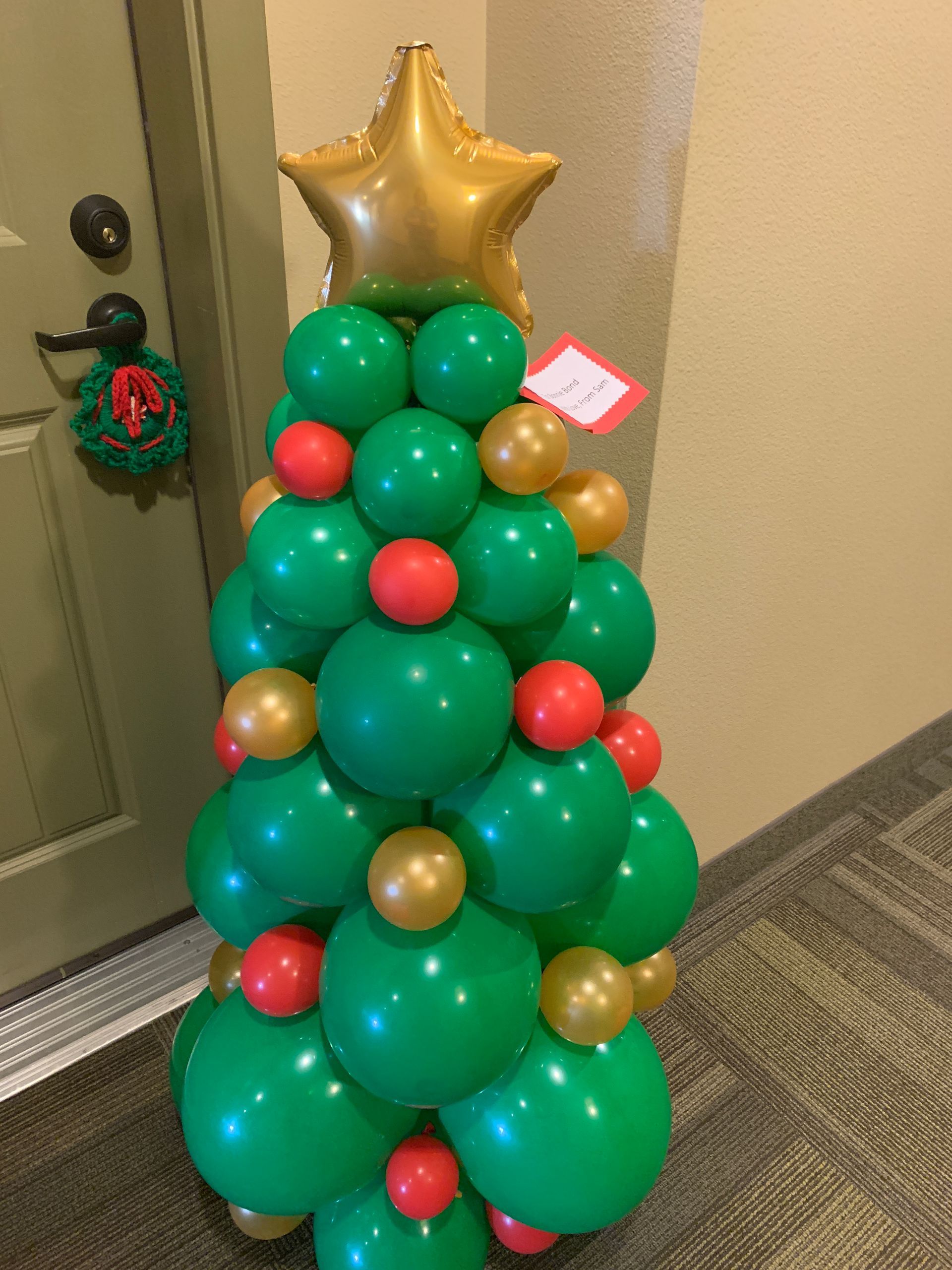 A christmas tree made out of green and gold balloons