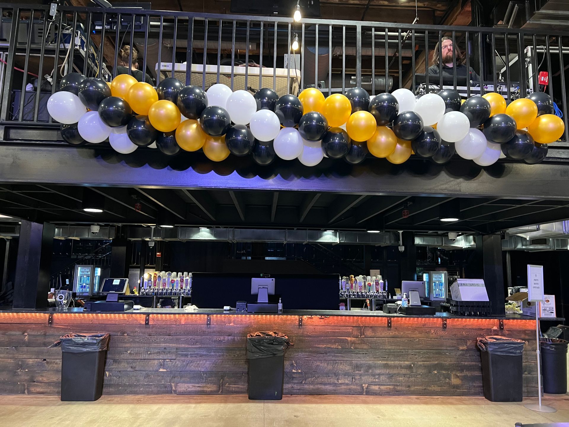 A bunch of balloons are hanging from the ceiling above a bar.