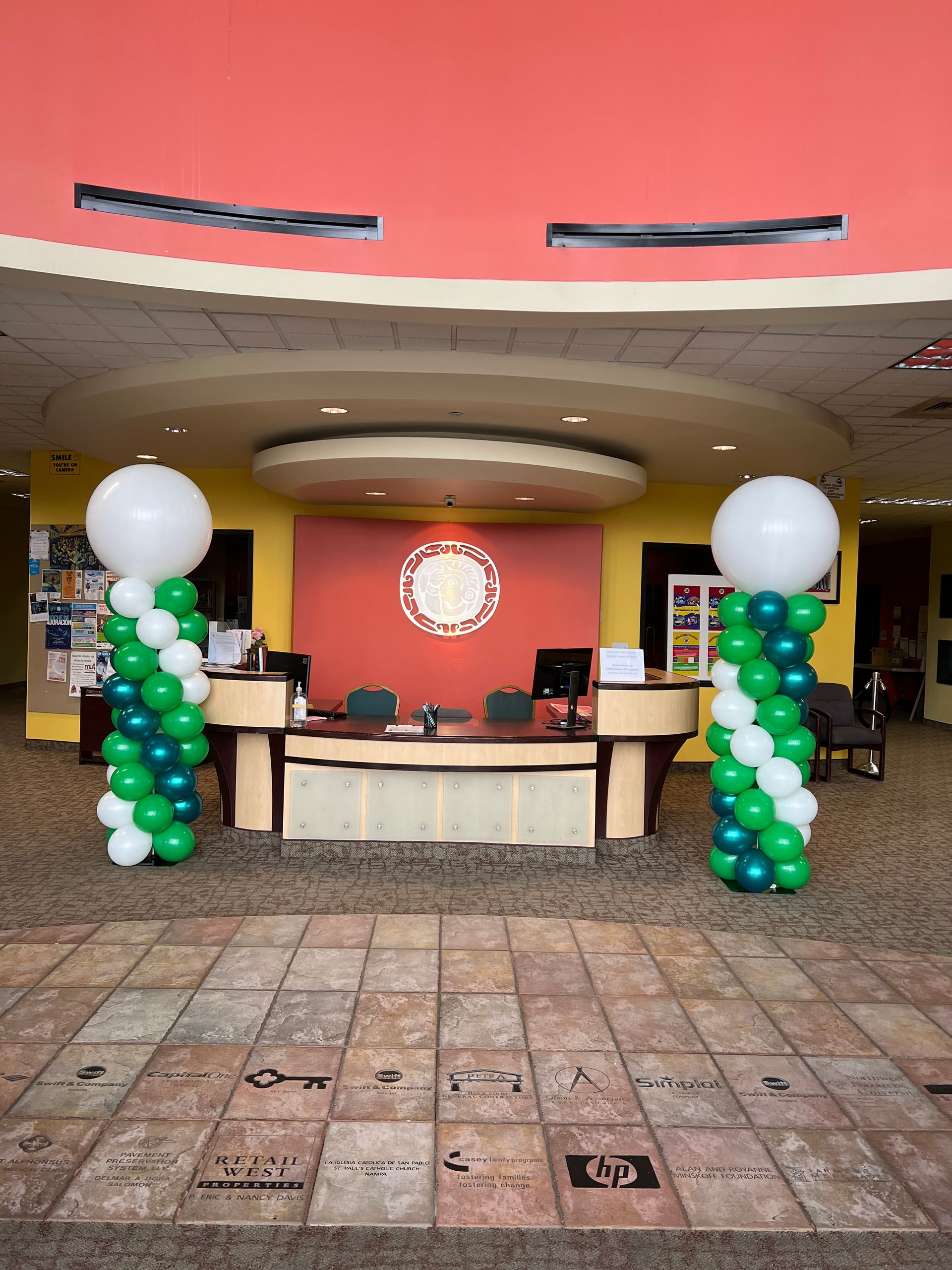 A lobby with green and white balloons in front of a desk