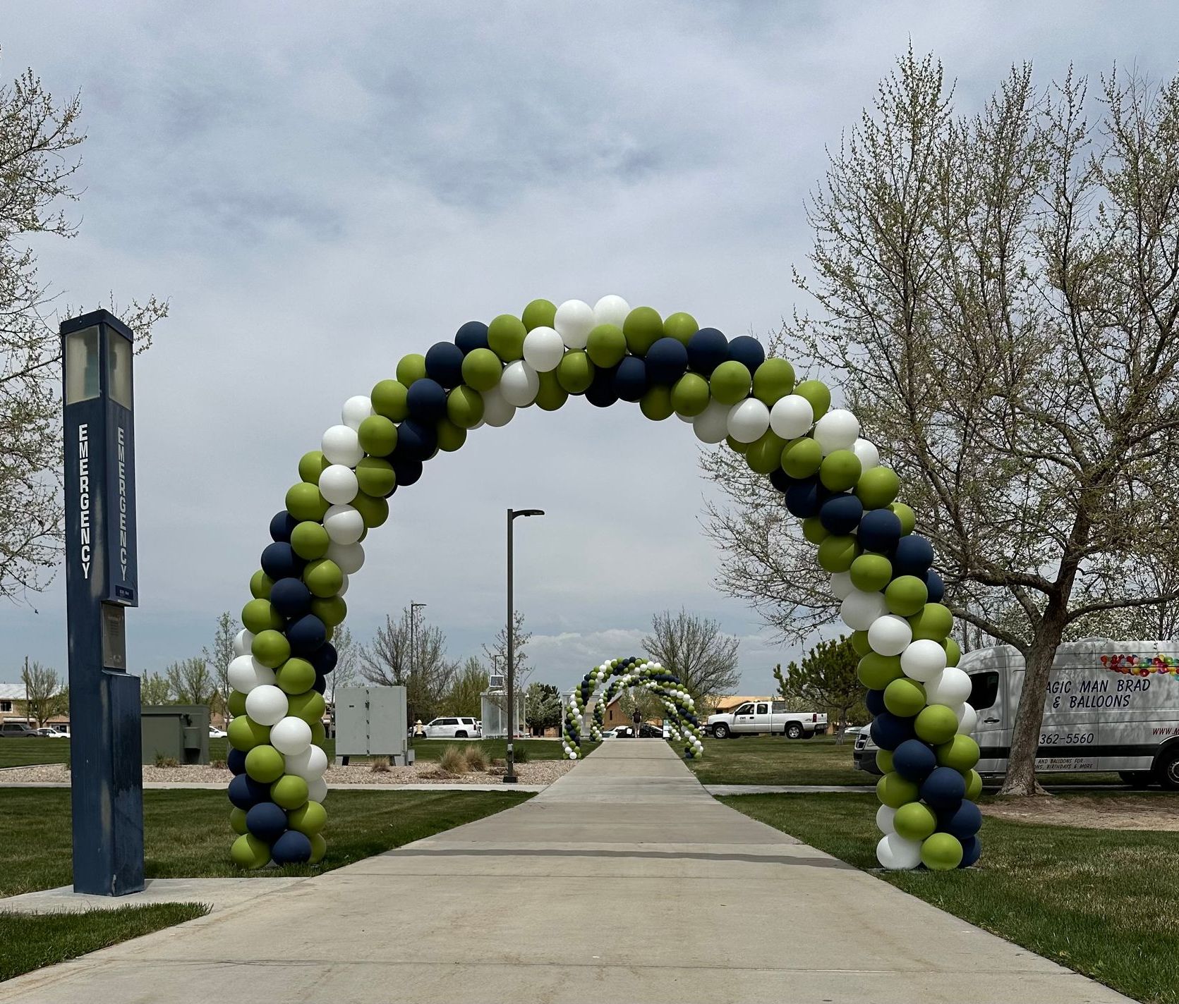 A large arch made of blue white and green balloons