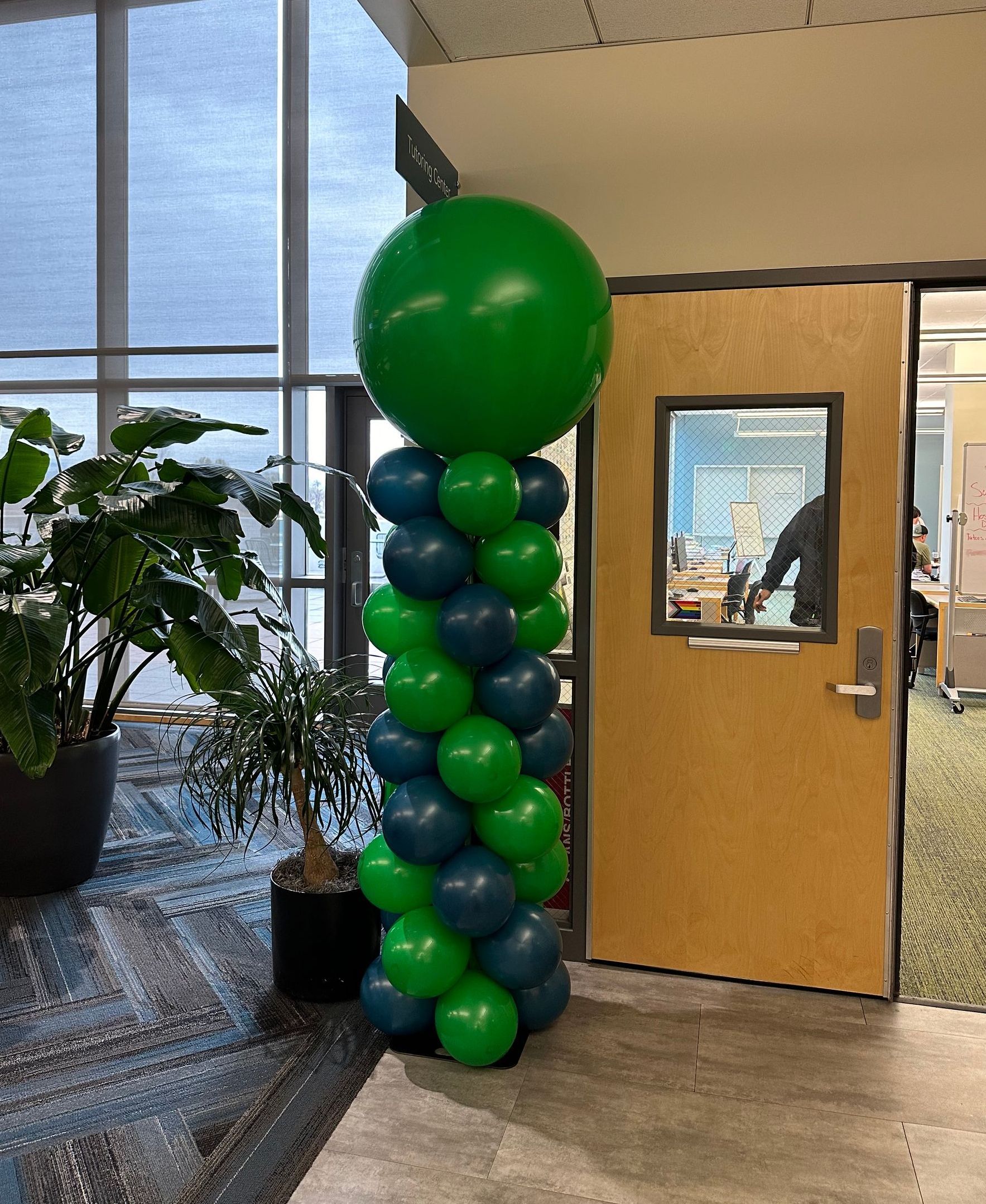 A green and blue balloon tower is in front of a door.