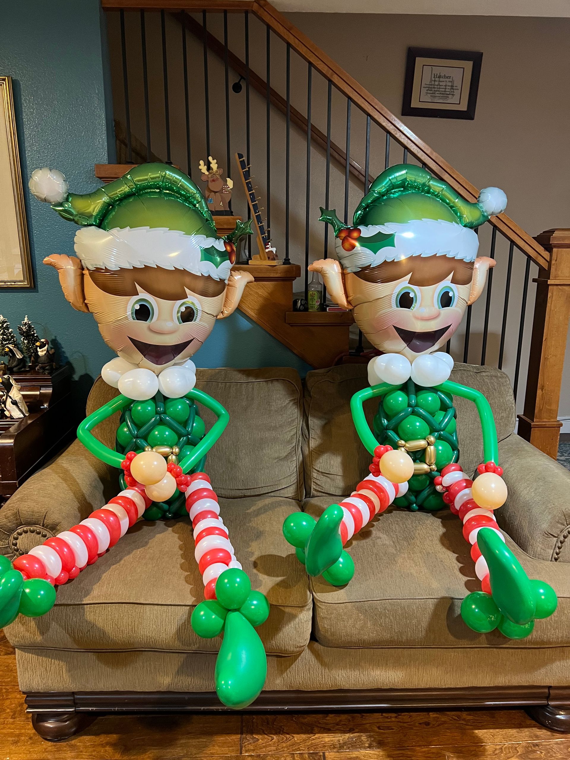 Two elf balloons are sitting on a couch in a living room.