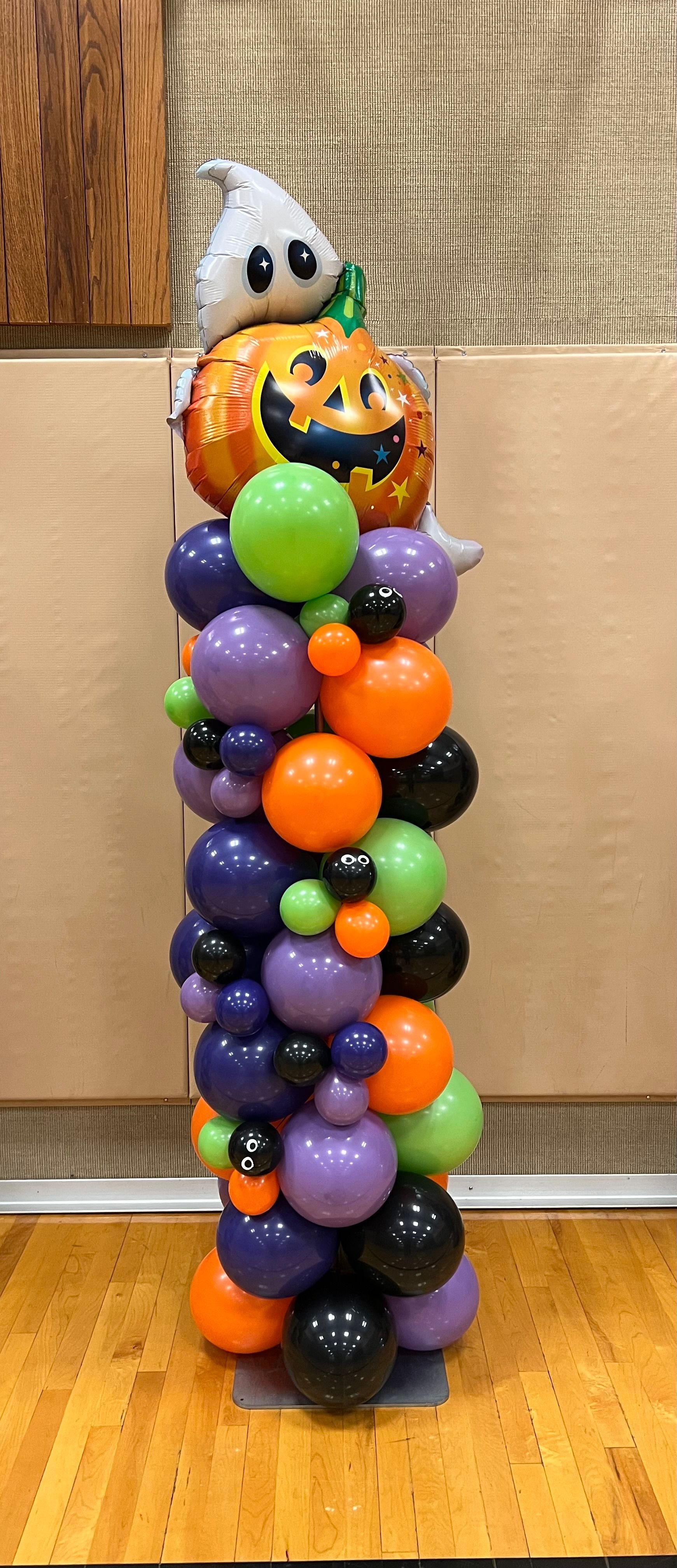 A stack of halloween balloons on a wooden floor.
