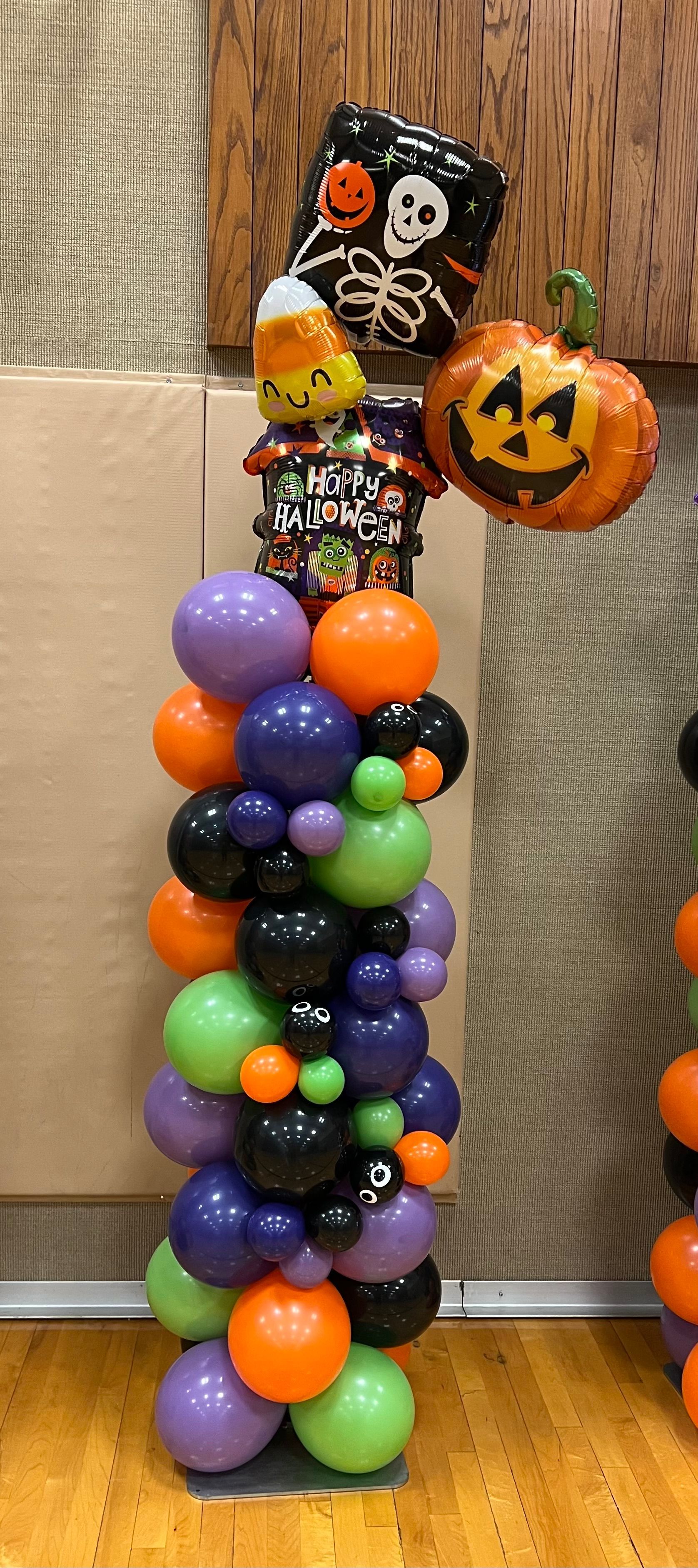 A balloon tower decorated for halloween is sitting on a wooden floor.