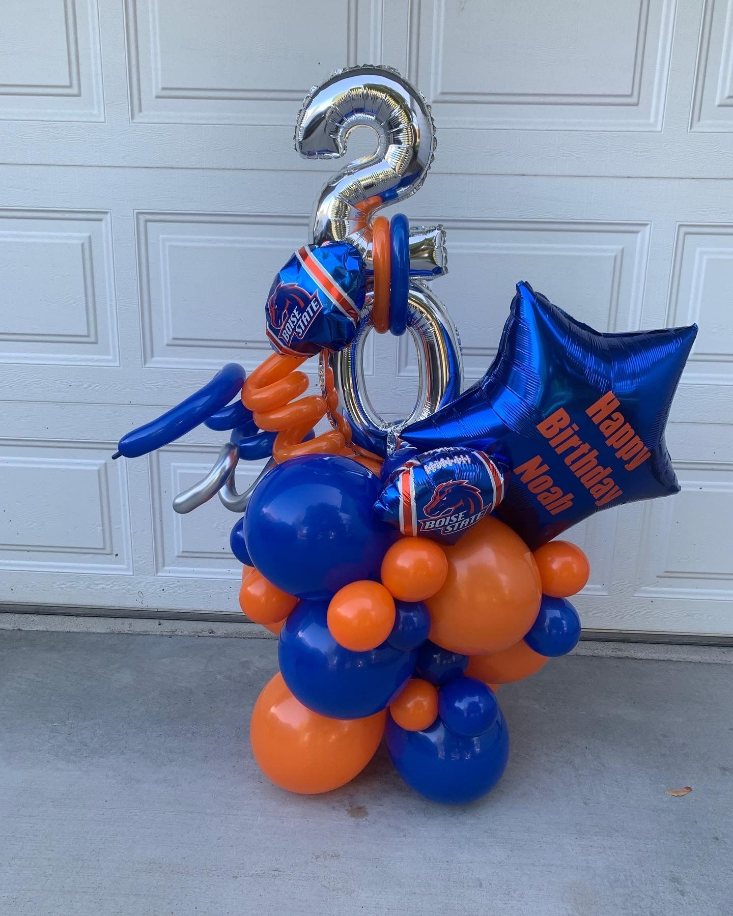 A bunch of blue and orange balloons are sitting in front of a garage door