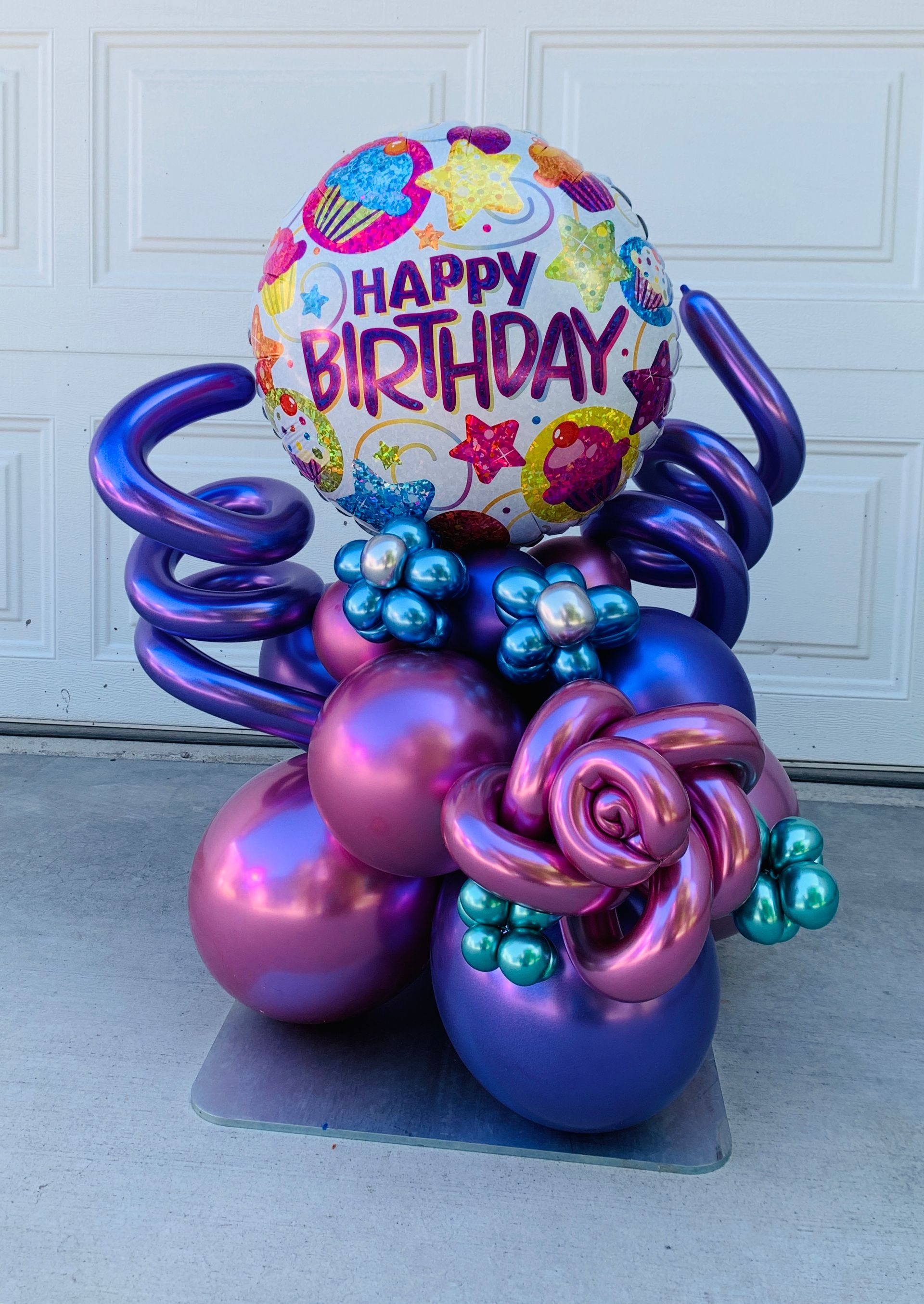 A happy birthday balloon is sitting on top of a bunch of balloons.