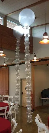 A room with tables and chairs and balloons hanging from the ceiling.