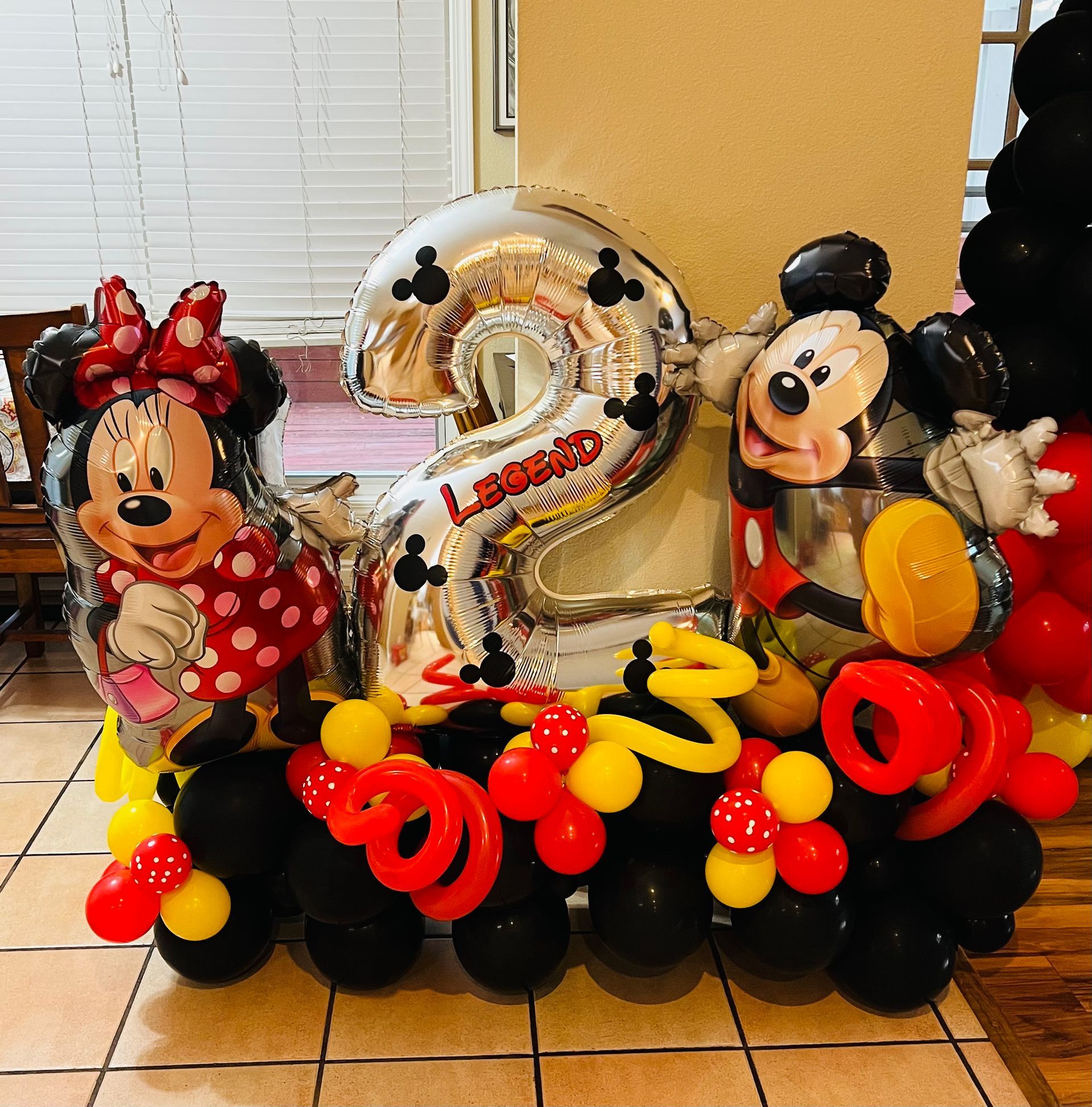 A bunch of mickey mouse and minnie mouse balloons on a tiled floor