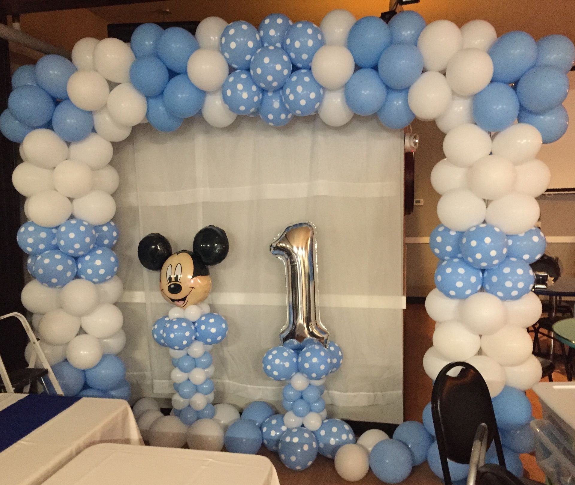 A room decorated with blue and white balloons and a mickey mouse balloon