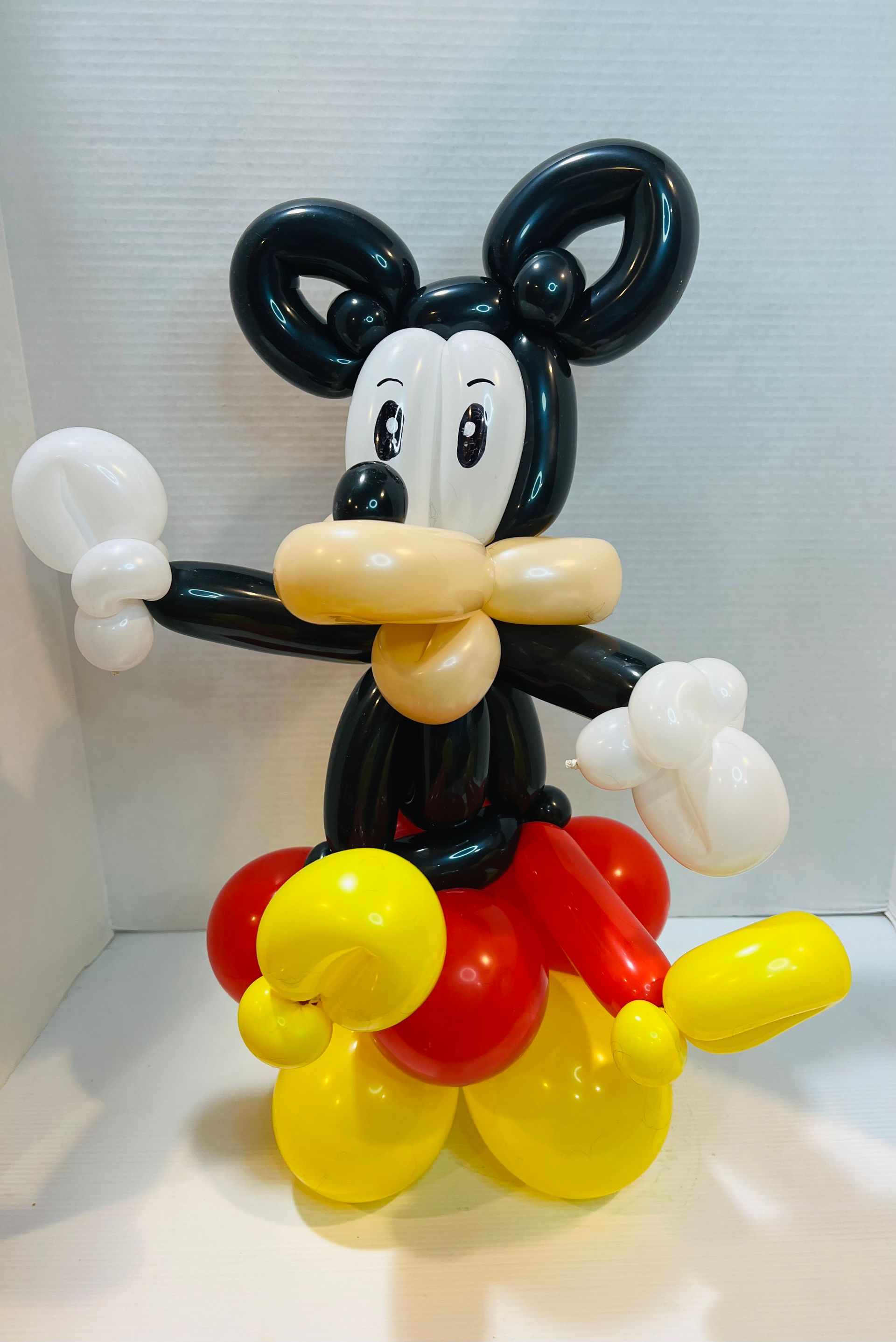A mickey mouse made out of balloons is standing on a table.