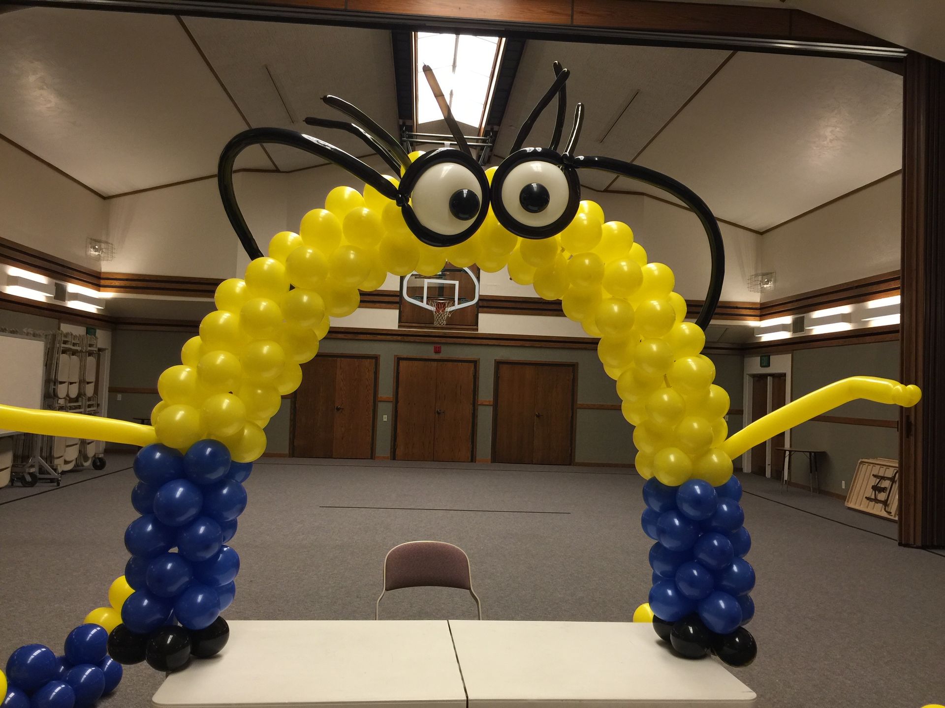A yellow and blue balloon arch in the shape of a minion