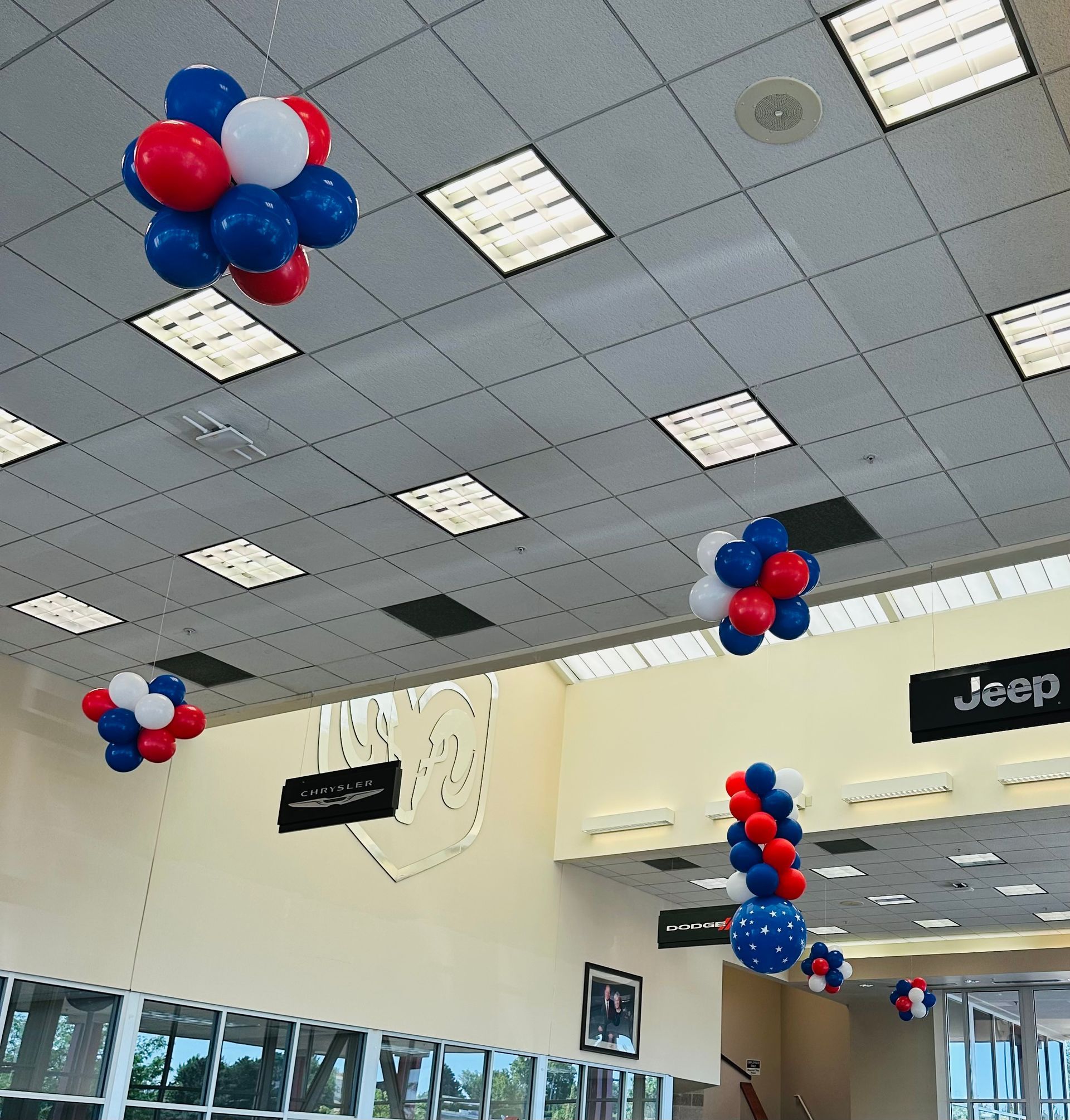 Red white and blue balloons hang from the ceiling of a jeep dealership