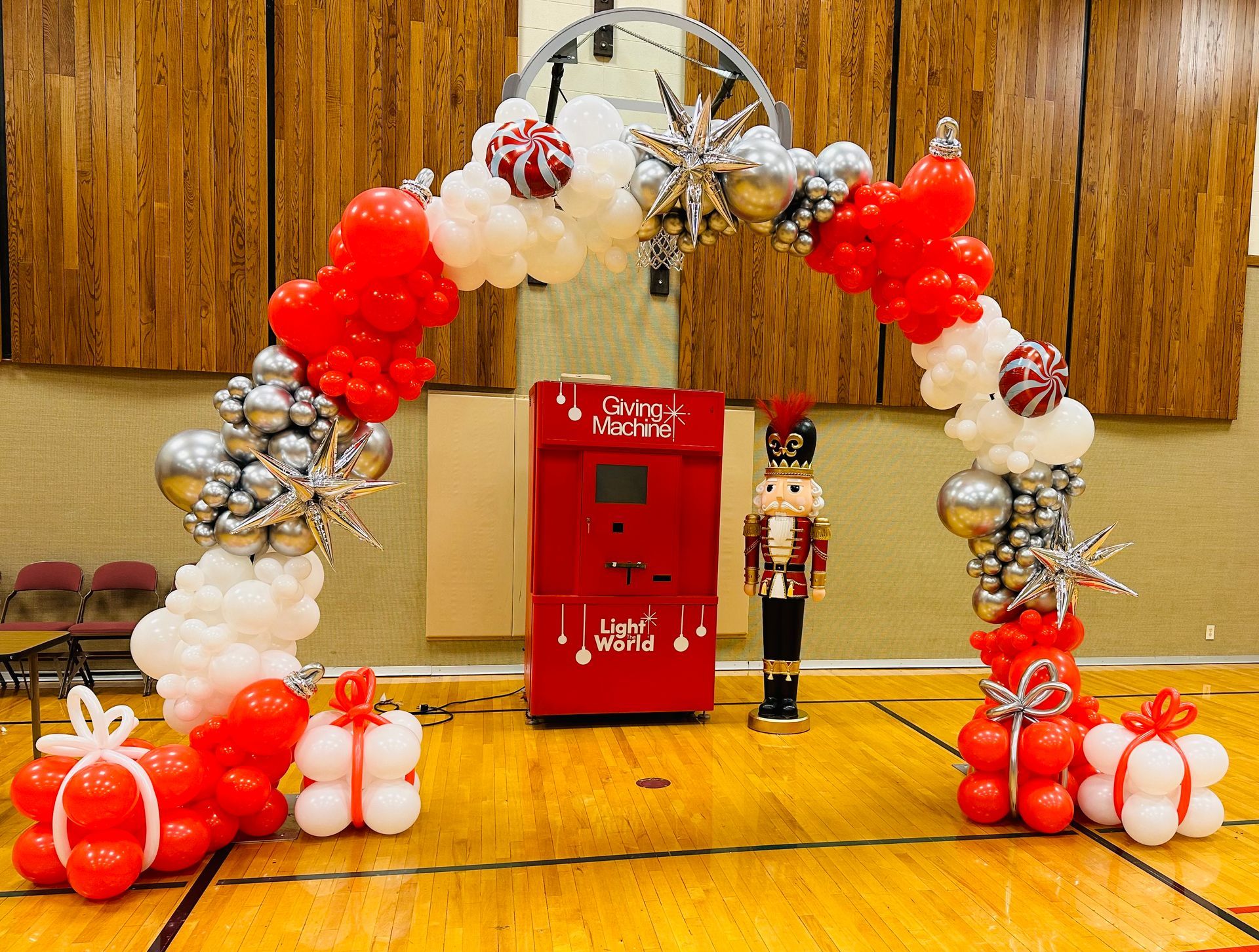 A basketball court decorated with red , white and silver balloons and a nutcracker.