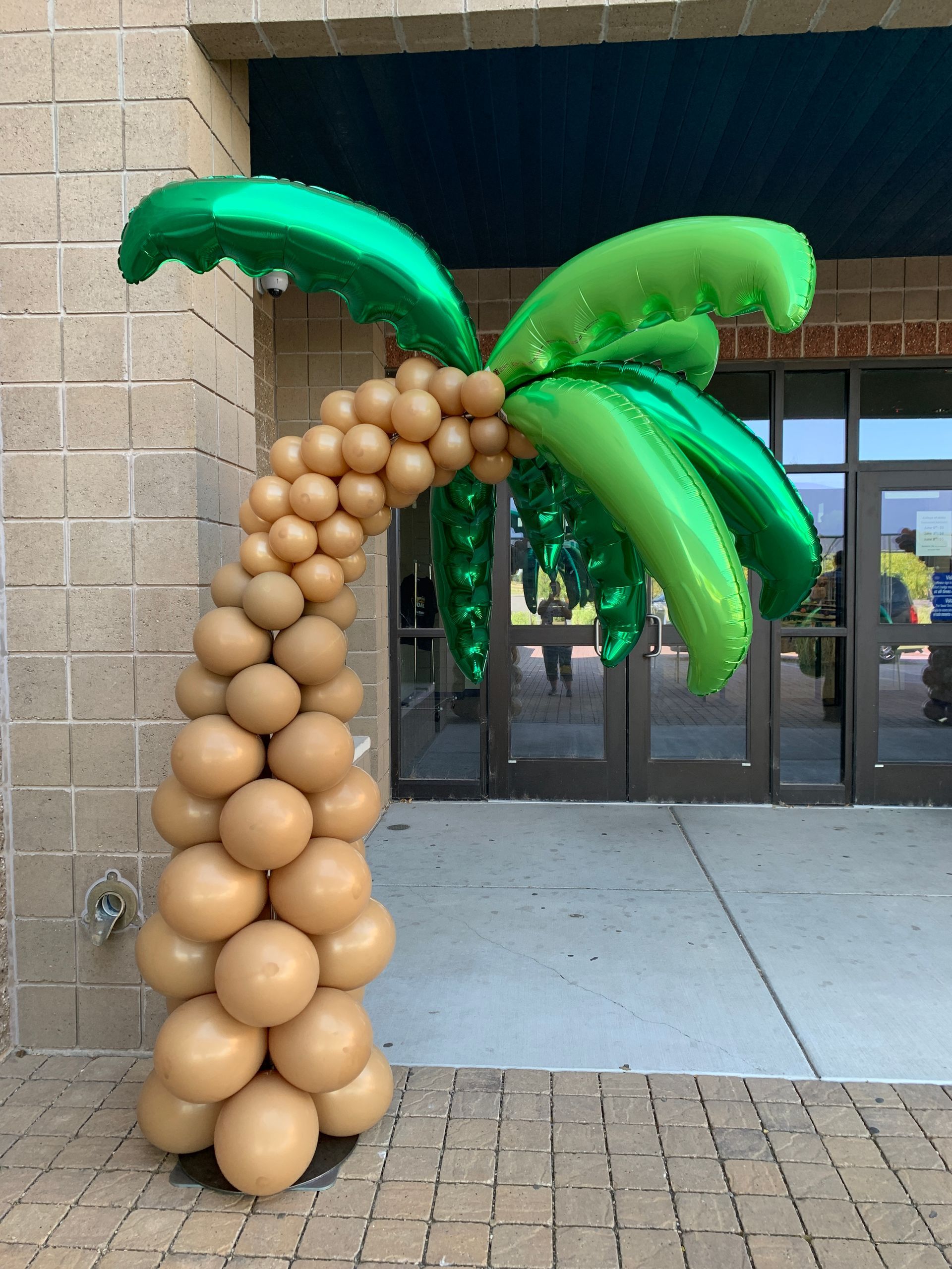 A palm tree made out of balloons in front of a building