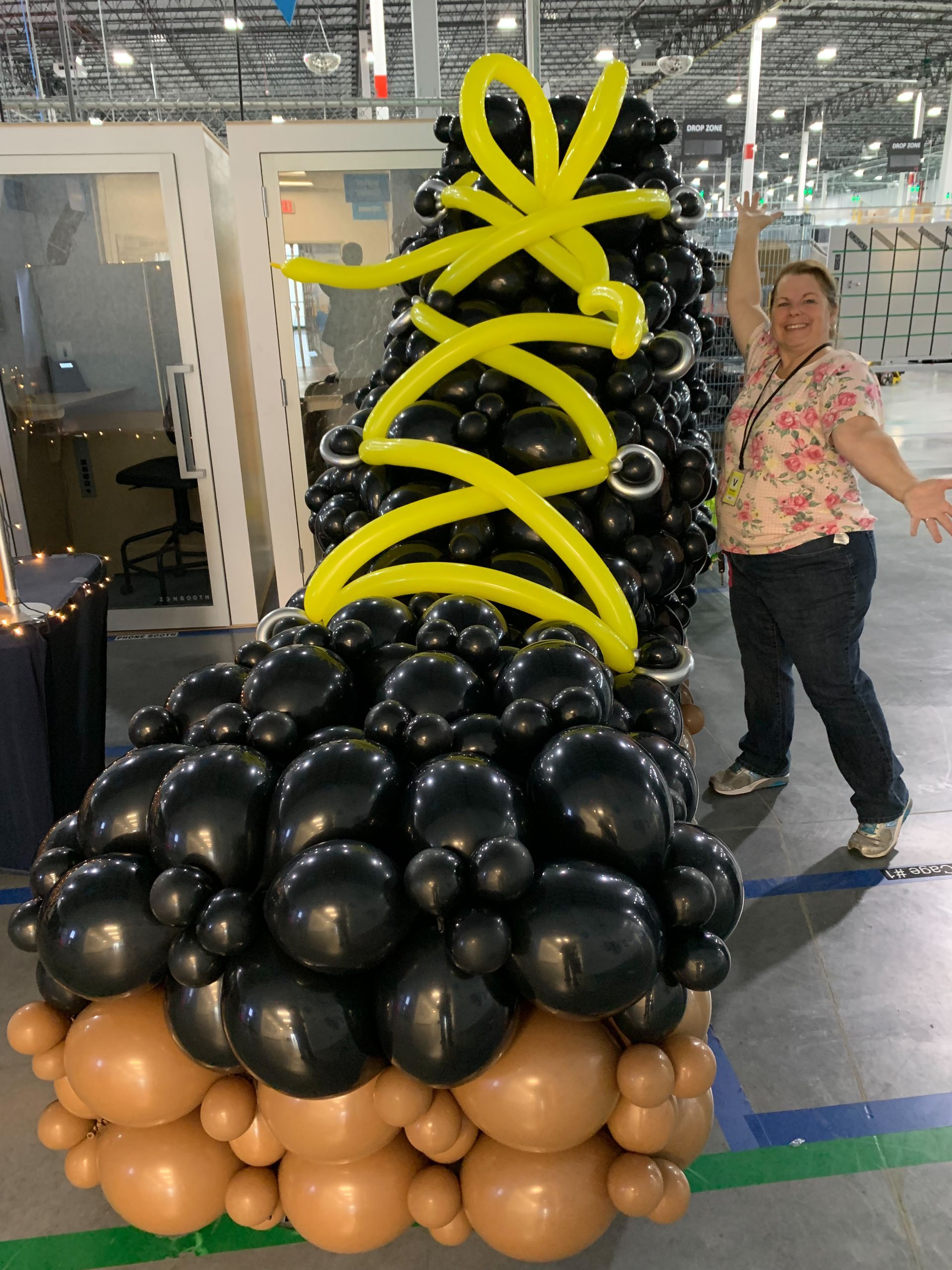 A woman is standing in front of a shoe made of balloons