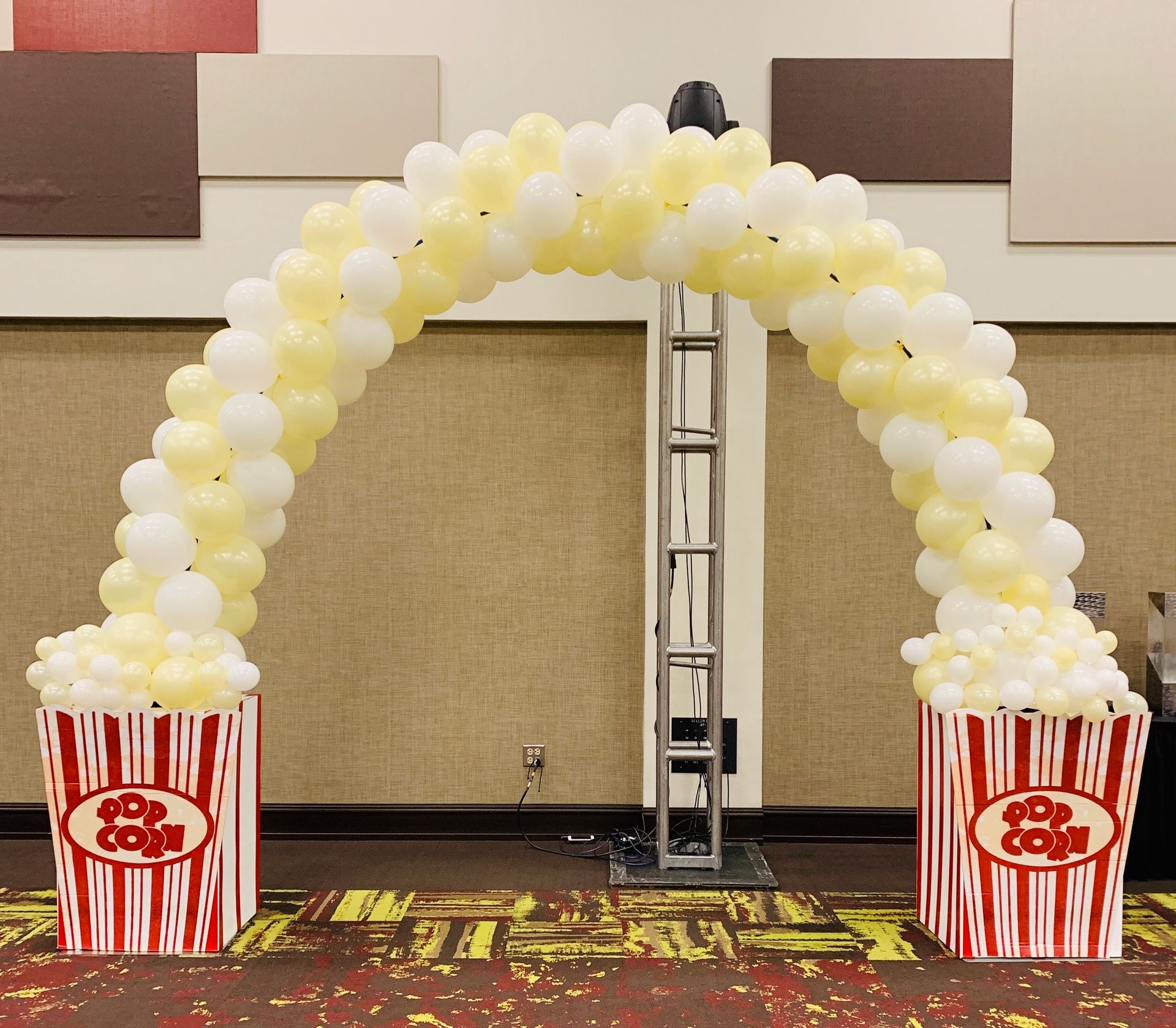 Two boxes of popcorn are under an arch of balloons