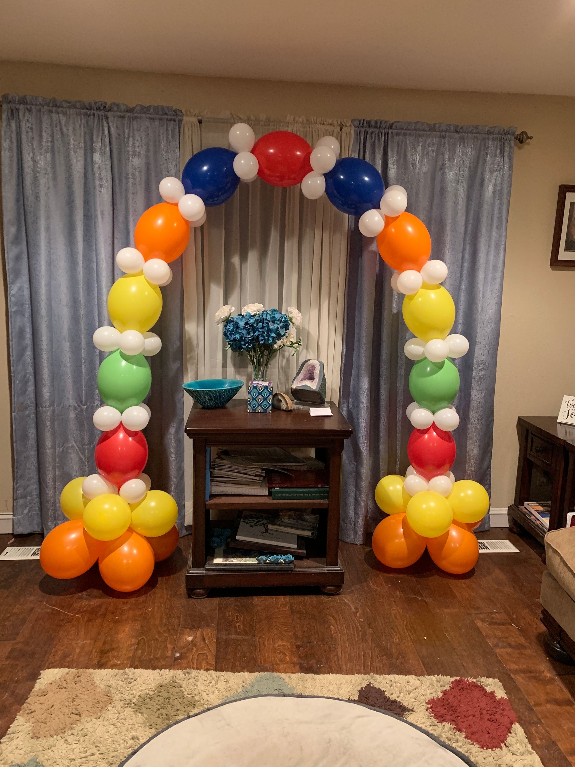 A living room decorated with balloons and a rainbow arch.