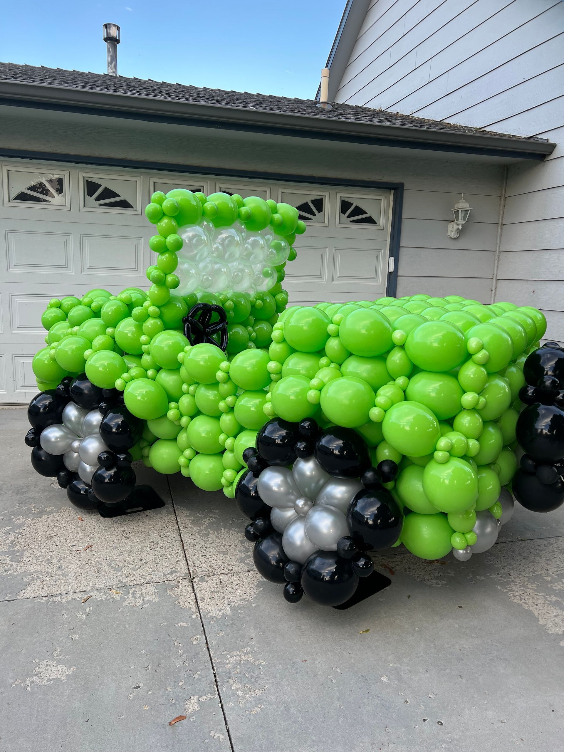 A green truck made out of green and black balloons