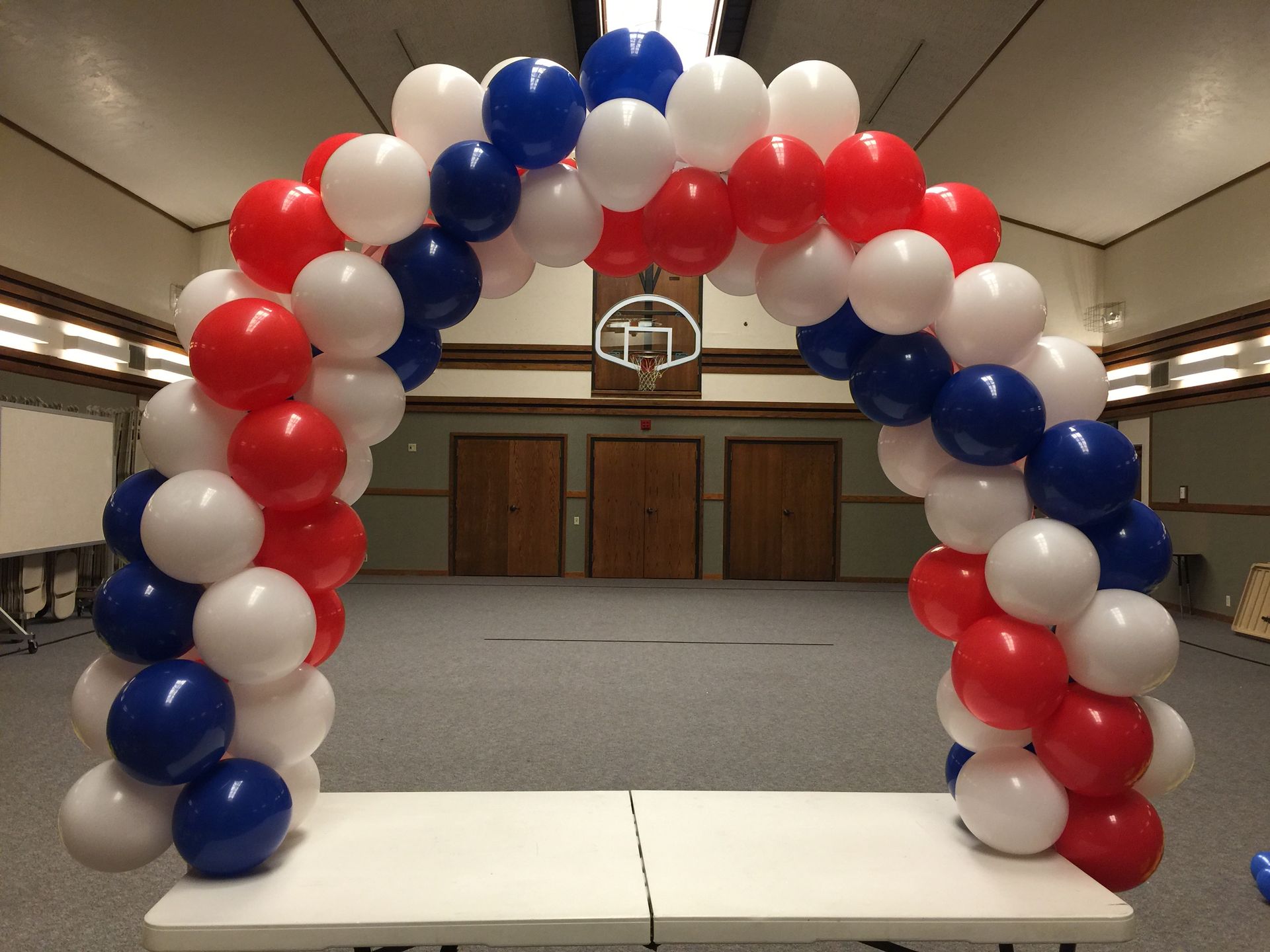 A red white and blue balloon arch in a room