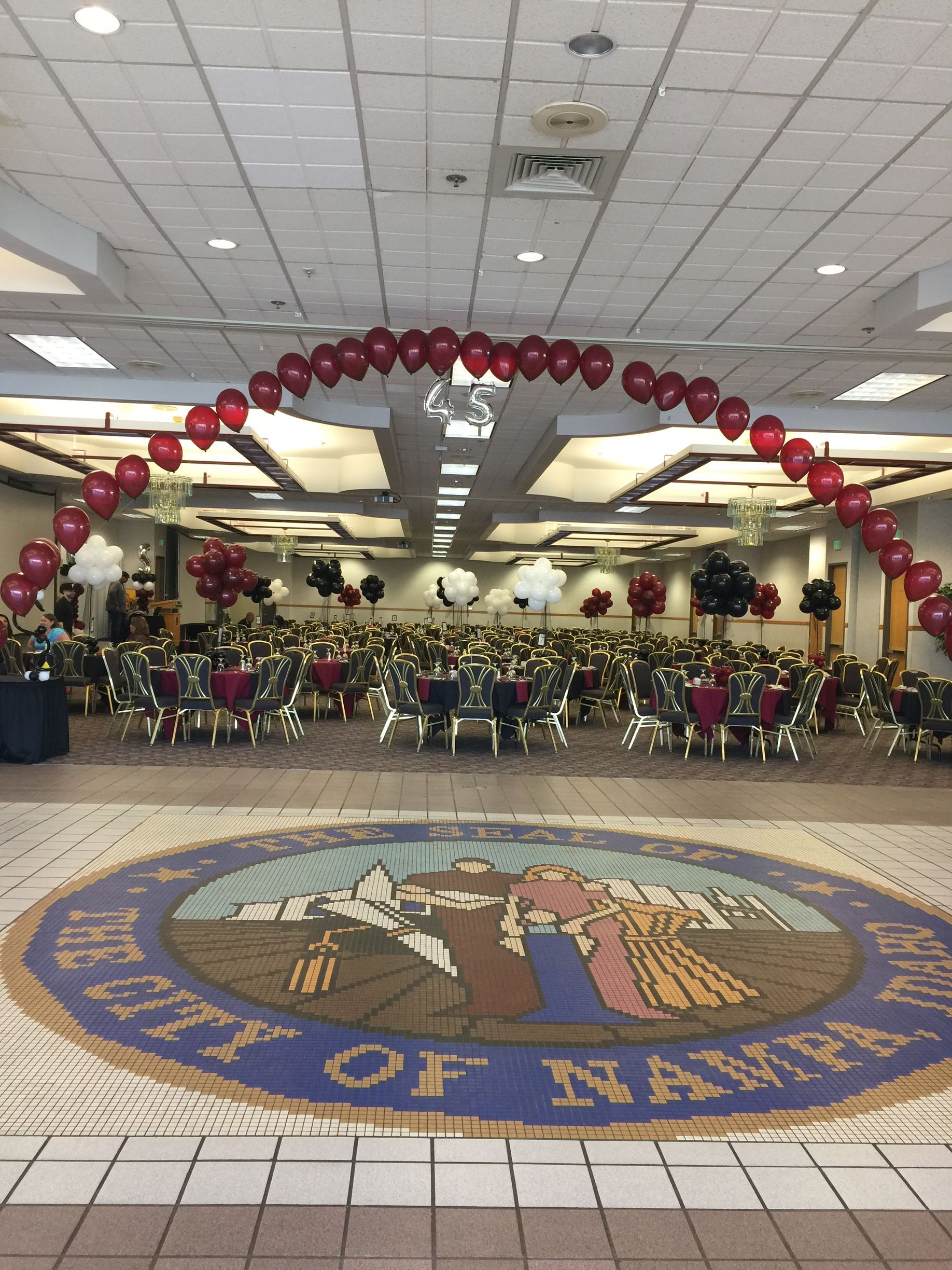 A large room with tables and chairs and balloons on the ceiling.
