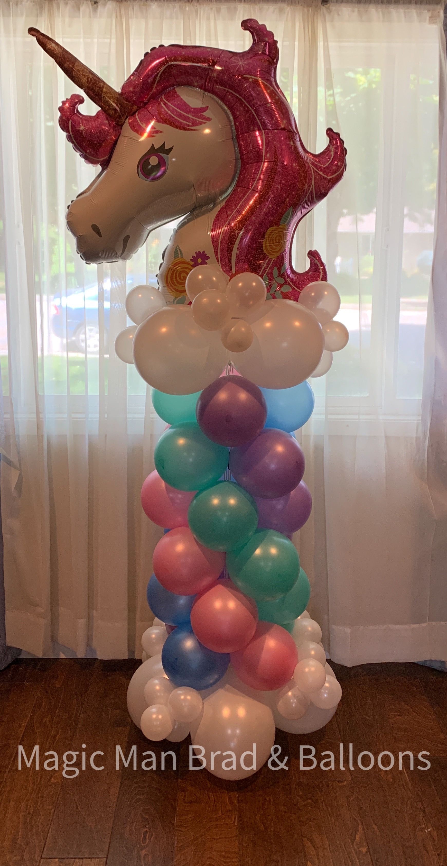 A unicorn balloon is sitting on top of a balloon tower.