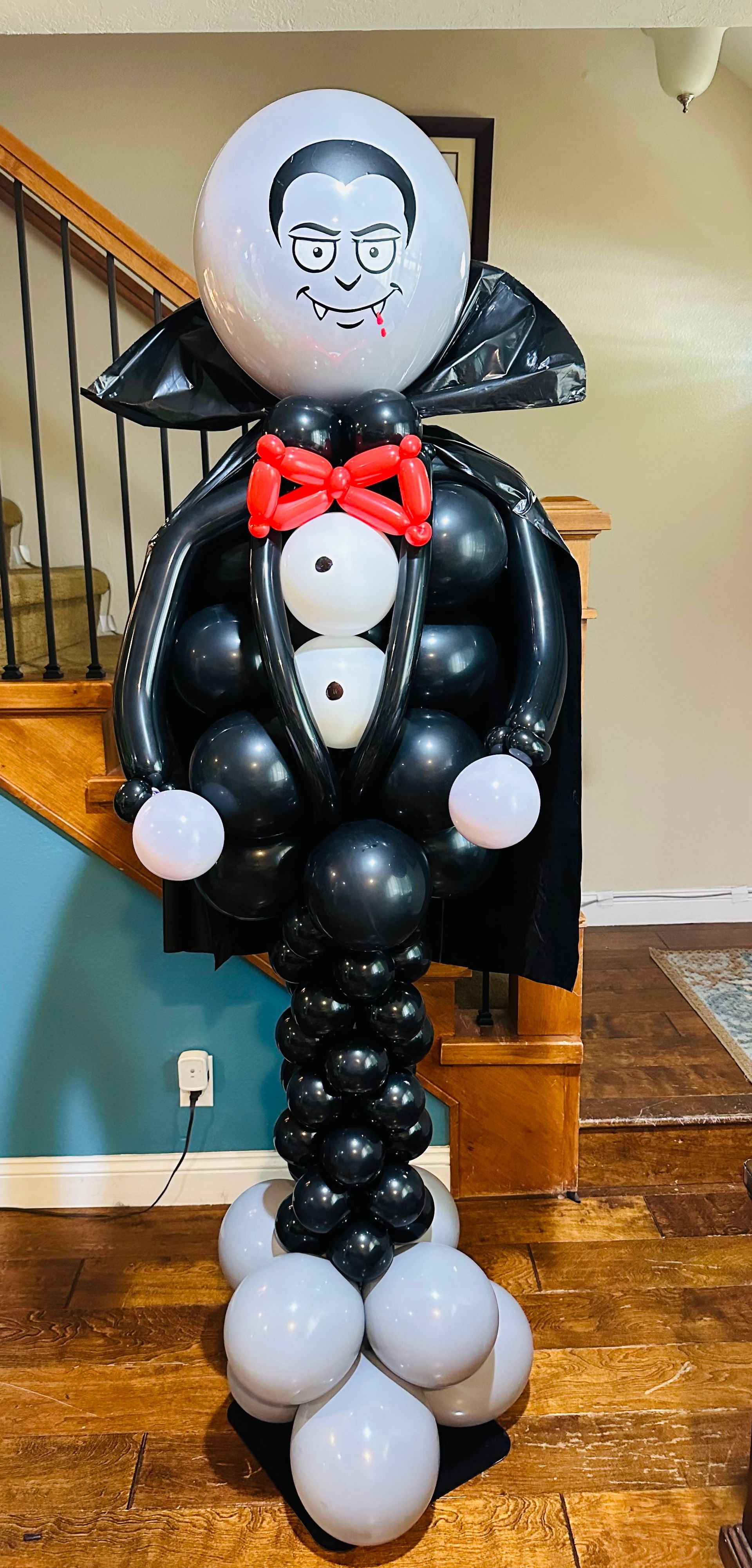 A vampire made out of balloons is standing in front of a staircase.