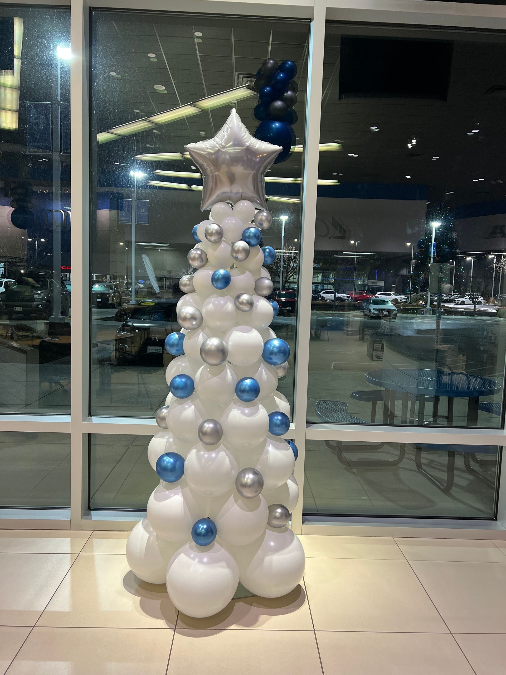 A christmas tree made out of balloons in front of a window.