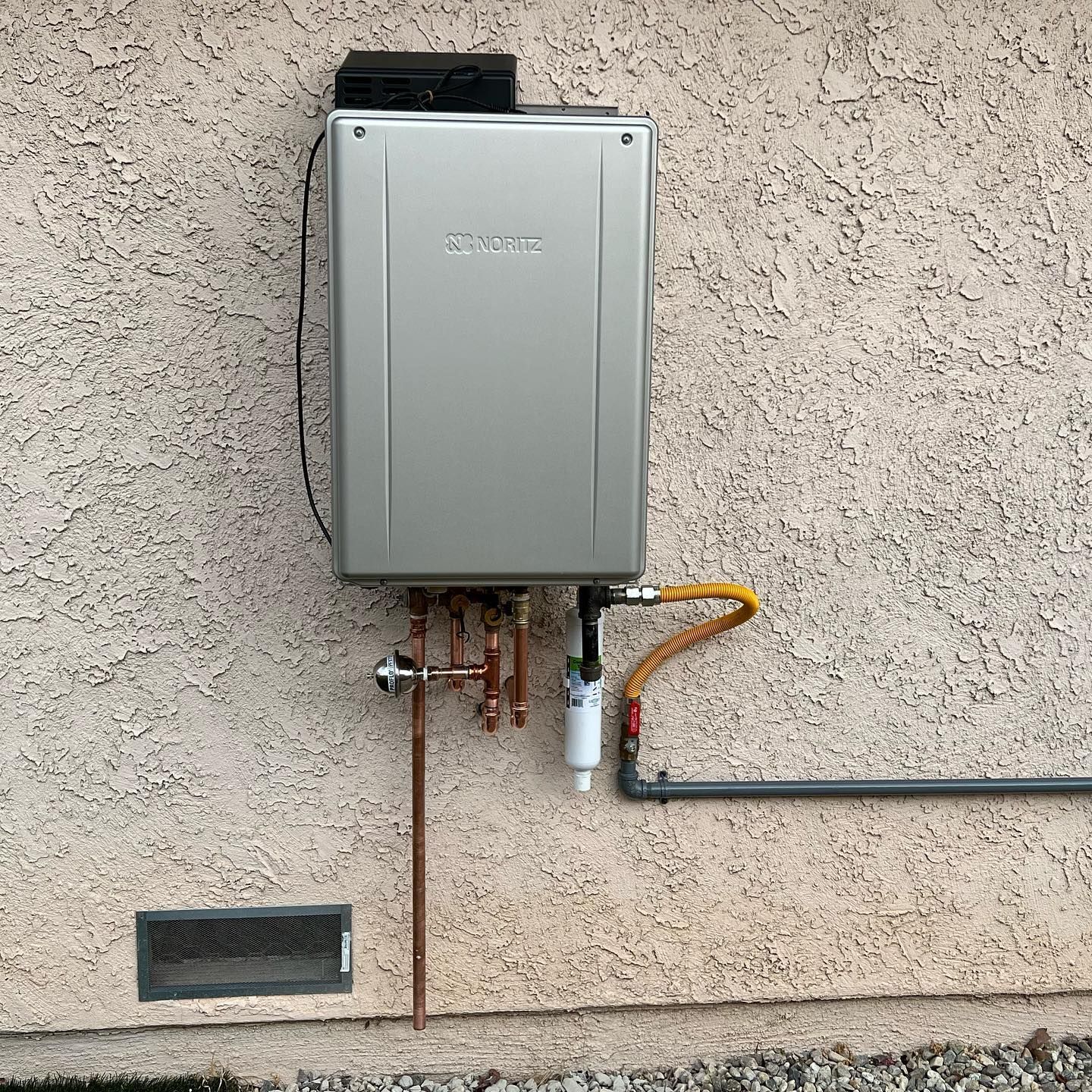 A gas water heater is attached to the side of a building.