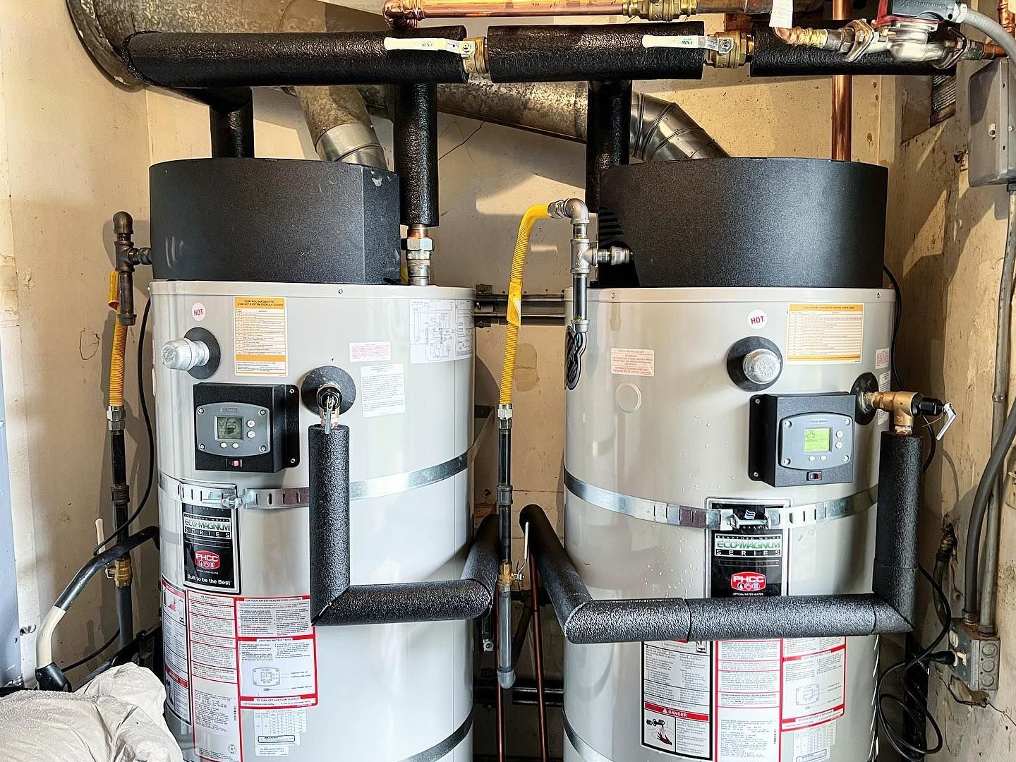Two water heaters are sitting next to each other in a room.