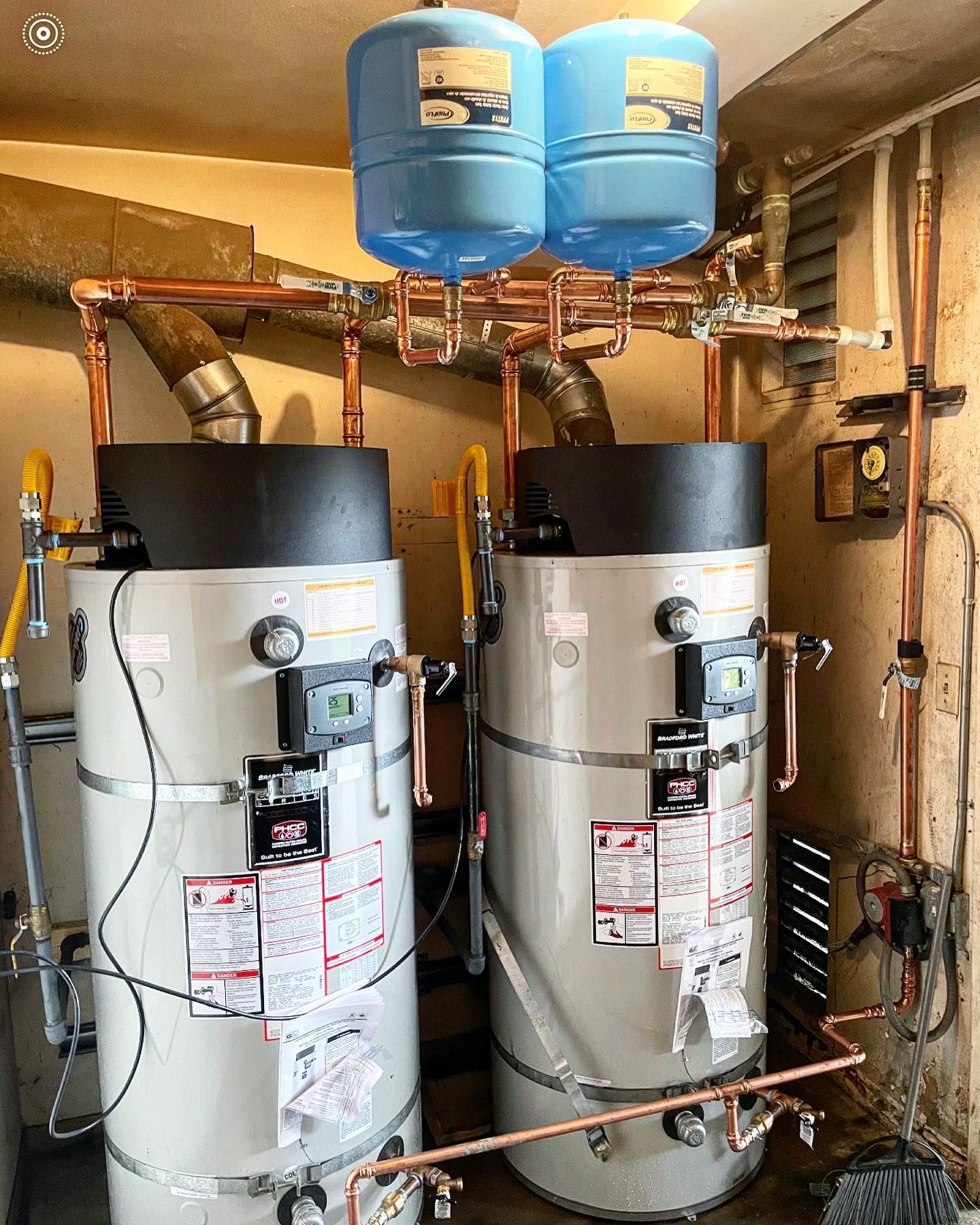 Two water heaters are sitting next to each other in a room.