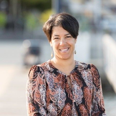 A woman in a paisley shirt is smiling for the camera.