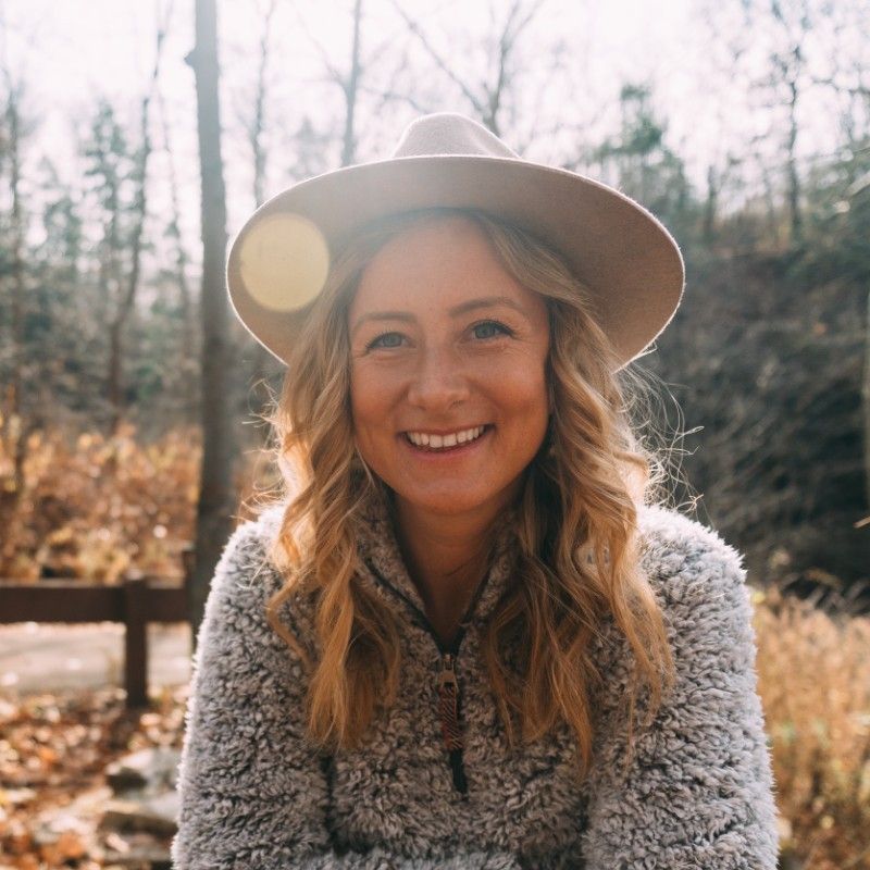 A woman wearing a hat and a sweater is smiling for the camera.