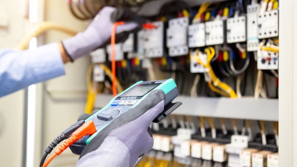 An electrician is using a multimeter to test a circuit board.