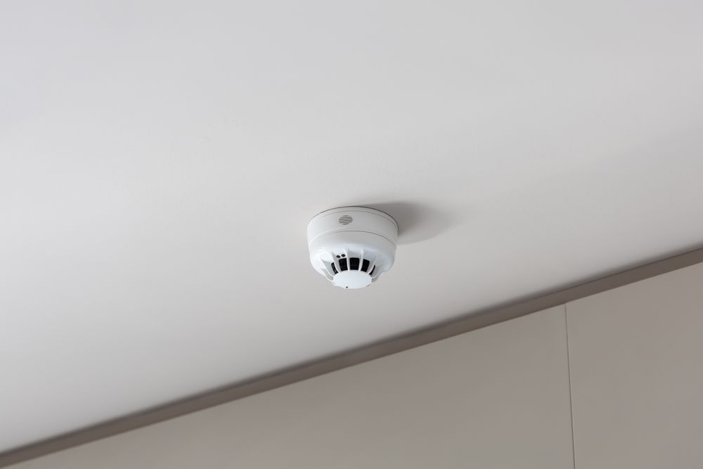 A smoke detector is mounted to the ceiling of a room.