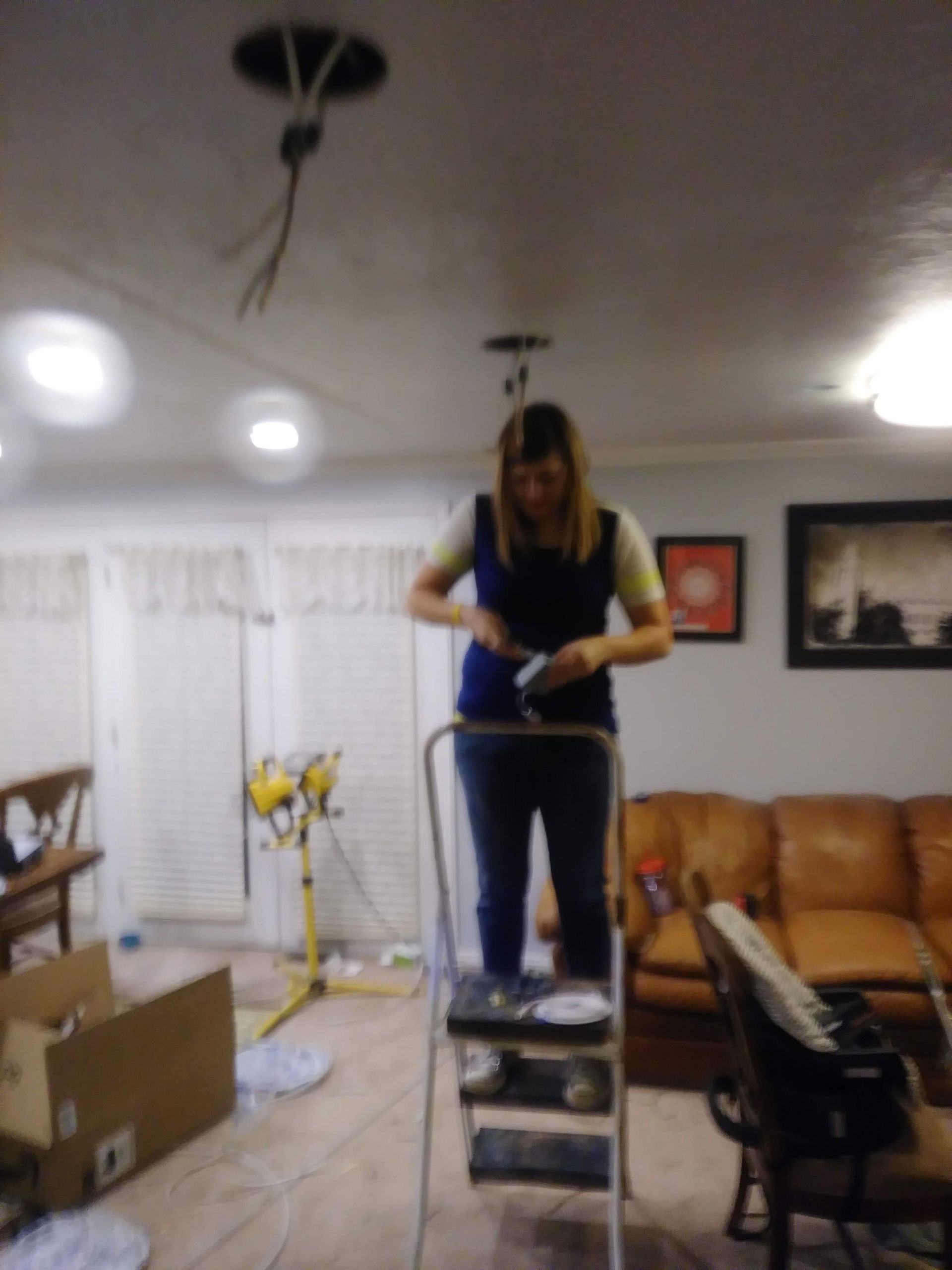 A woman is standing on a ladder in a living room