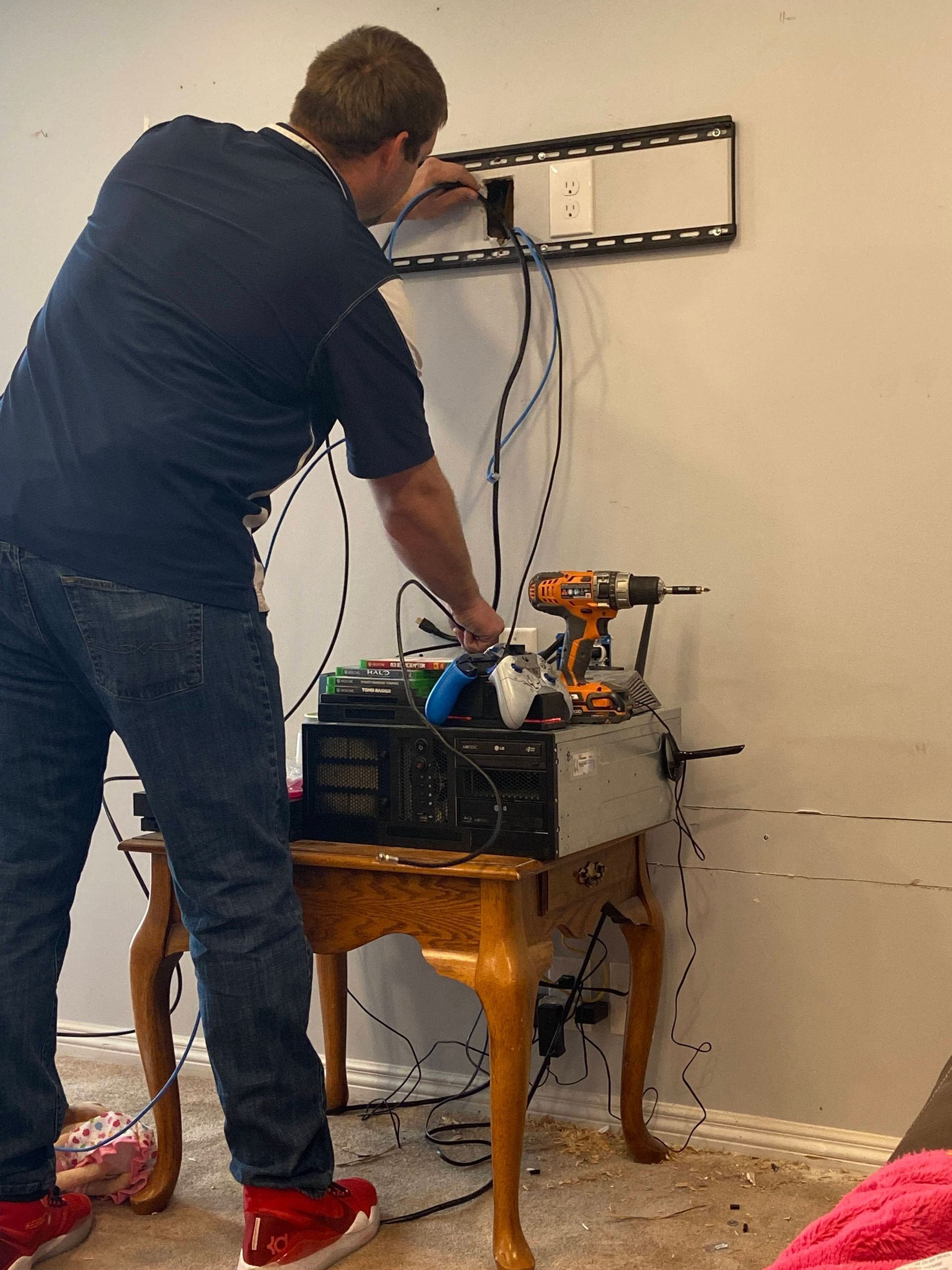 A man is working on a tv mount in a living room