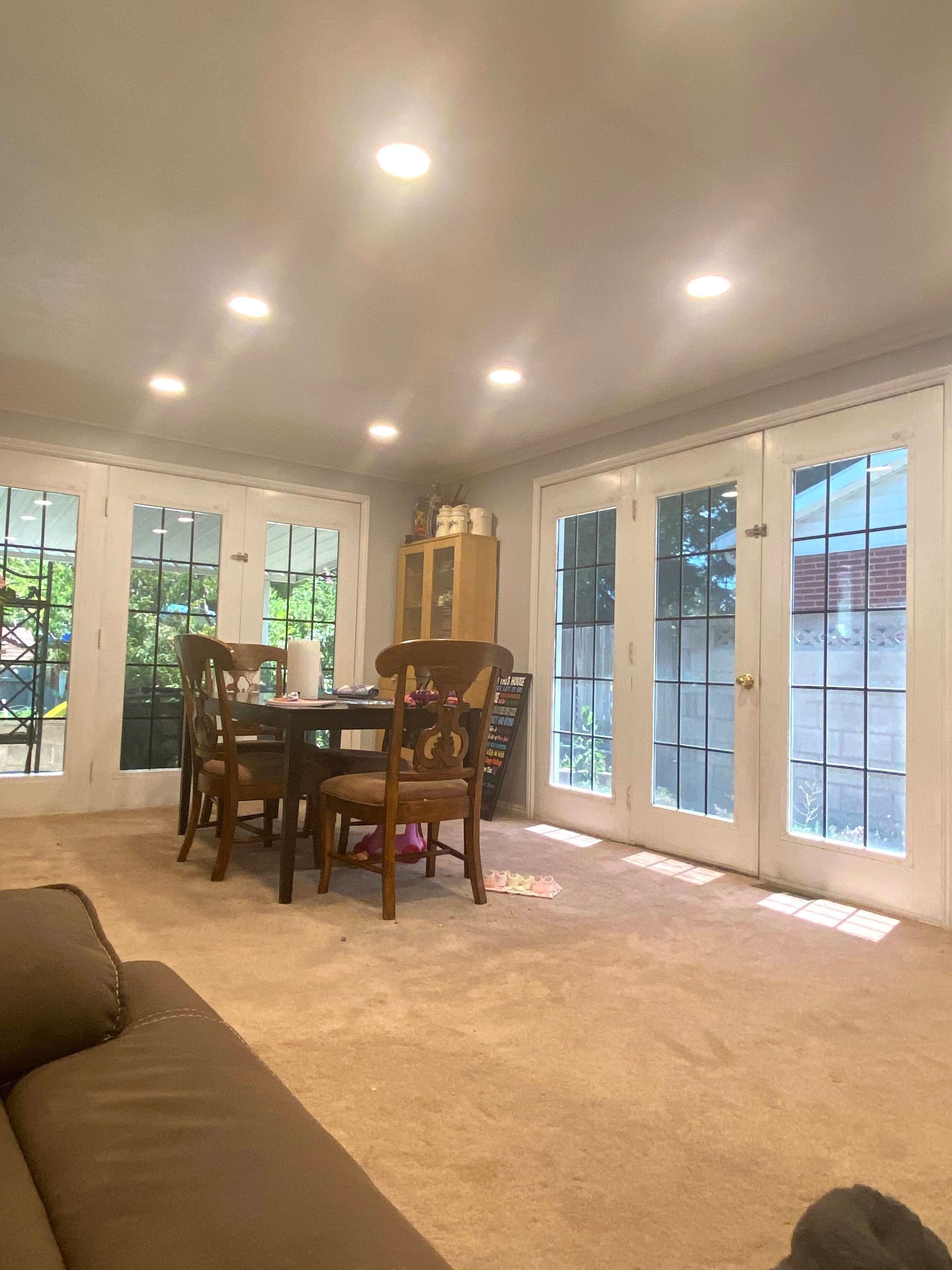 A living room with a table and chairs and a lot of windows.