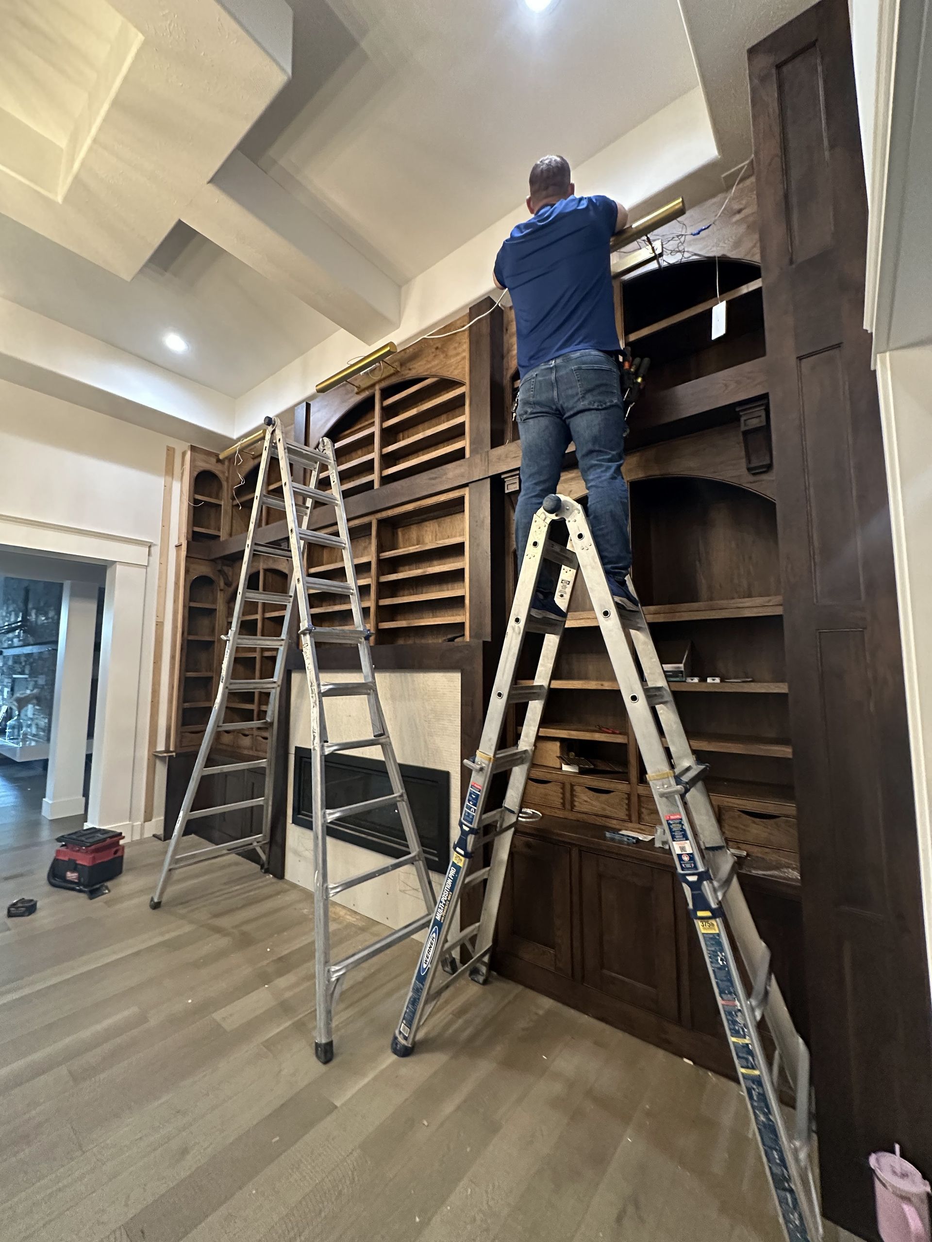 A man is standing on a ladder in a living room.