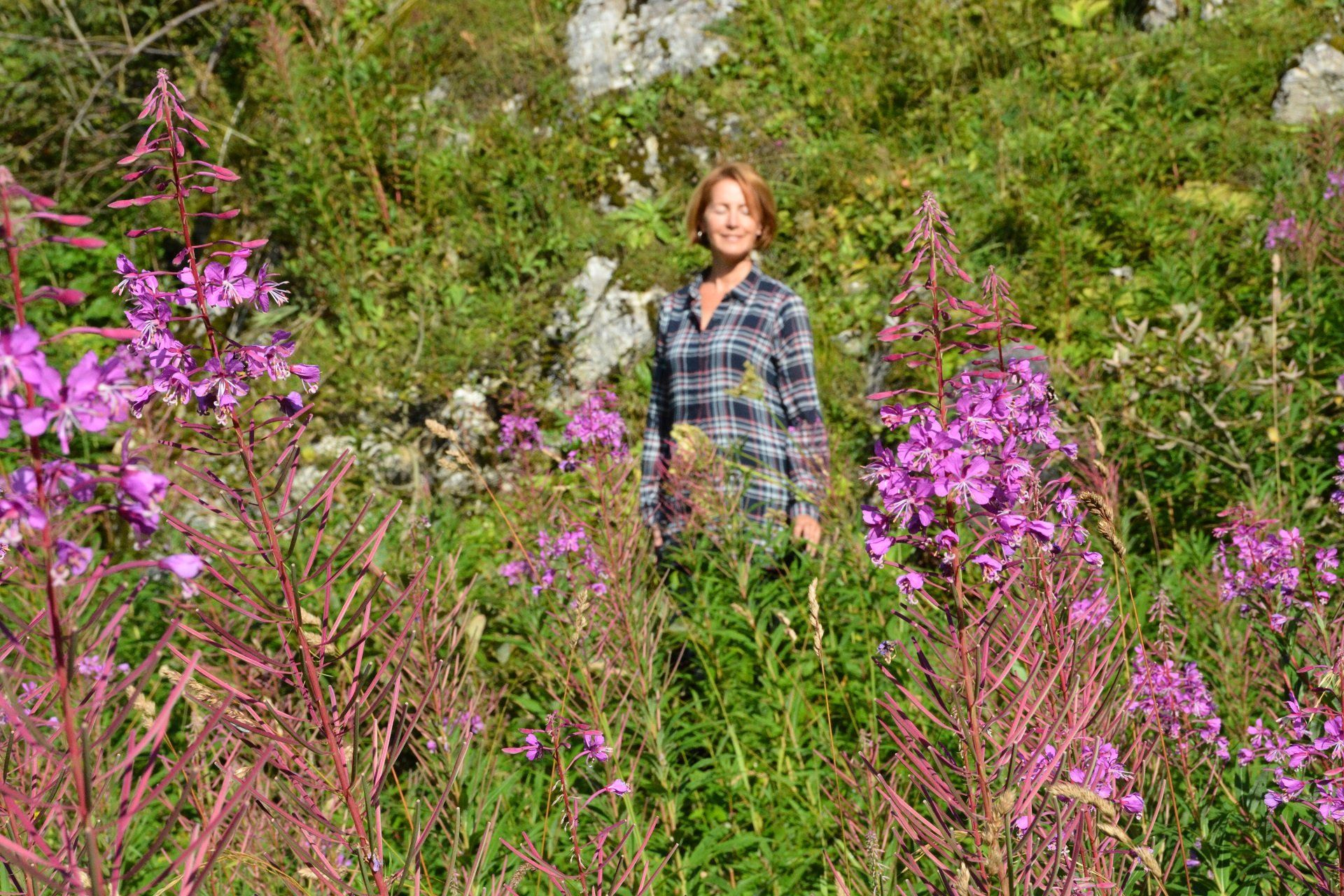 Eine Frau steht auf einem Feld mit lila Blumen.
