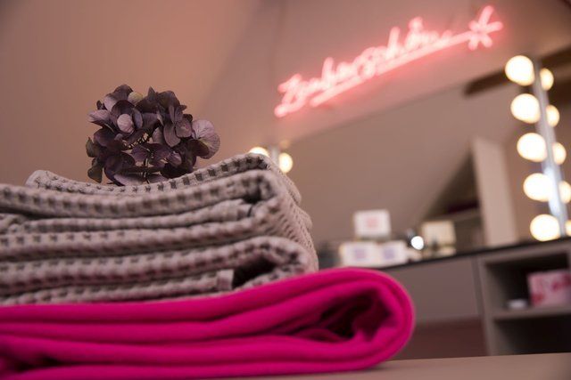 Ein Stapel Handtücher liegt auf einem Tisch vor einem Neonschild mit der Aufschrift „Brooklyn“