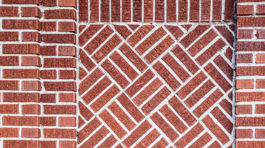 “Decorative red brick wall with a herringbone pattern and clean mortar joints from a masonry service in Missouri City, TX”