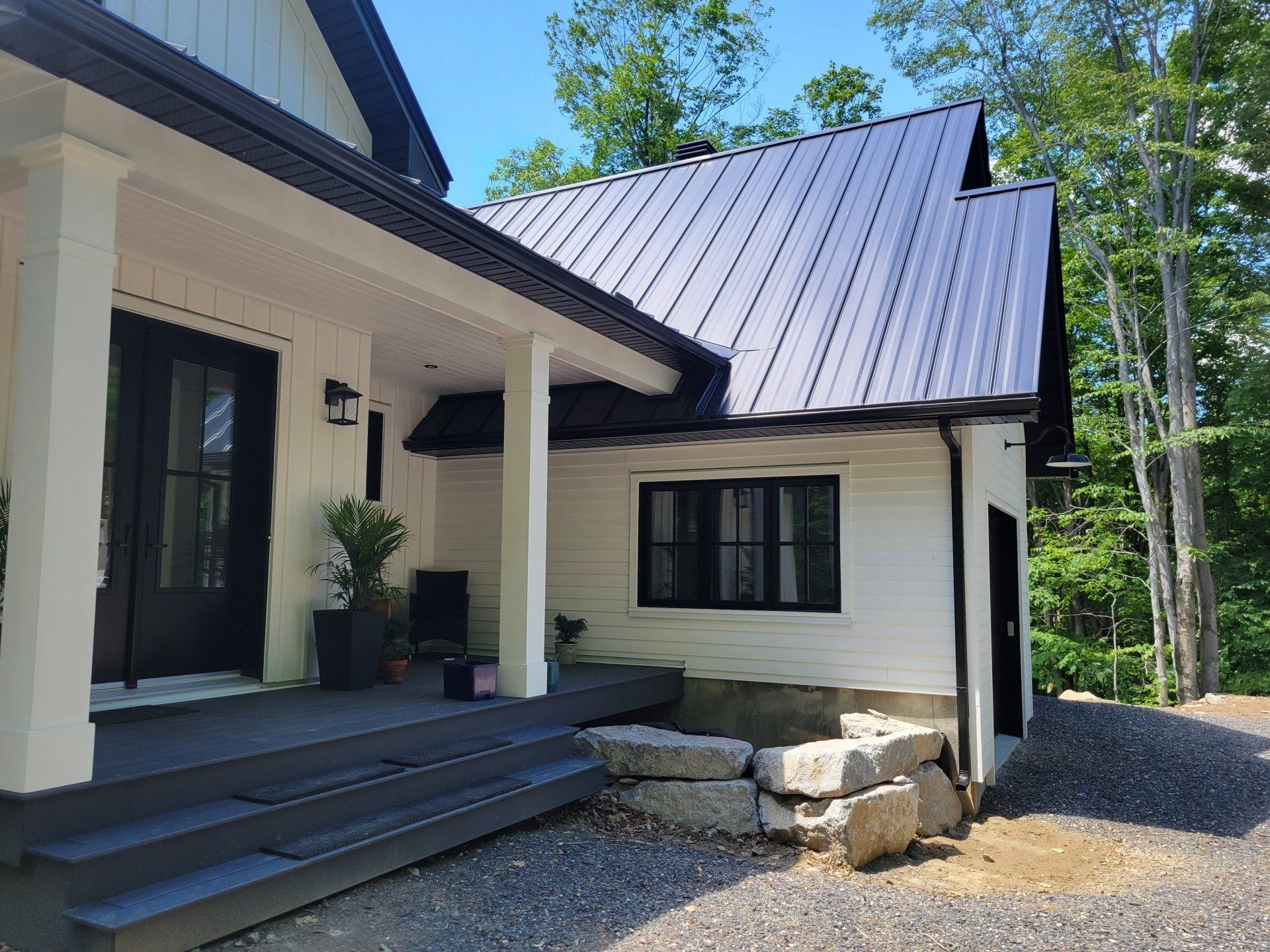 Une maison blanche avec un toit noir et des fenêtres noires