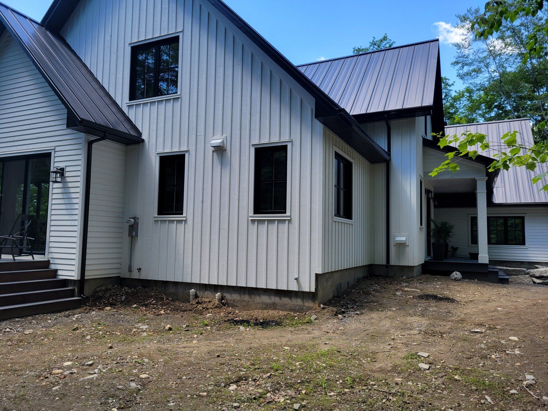 Une maison blanche avec un toit noir et beaucoup de fenêtres