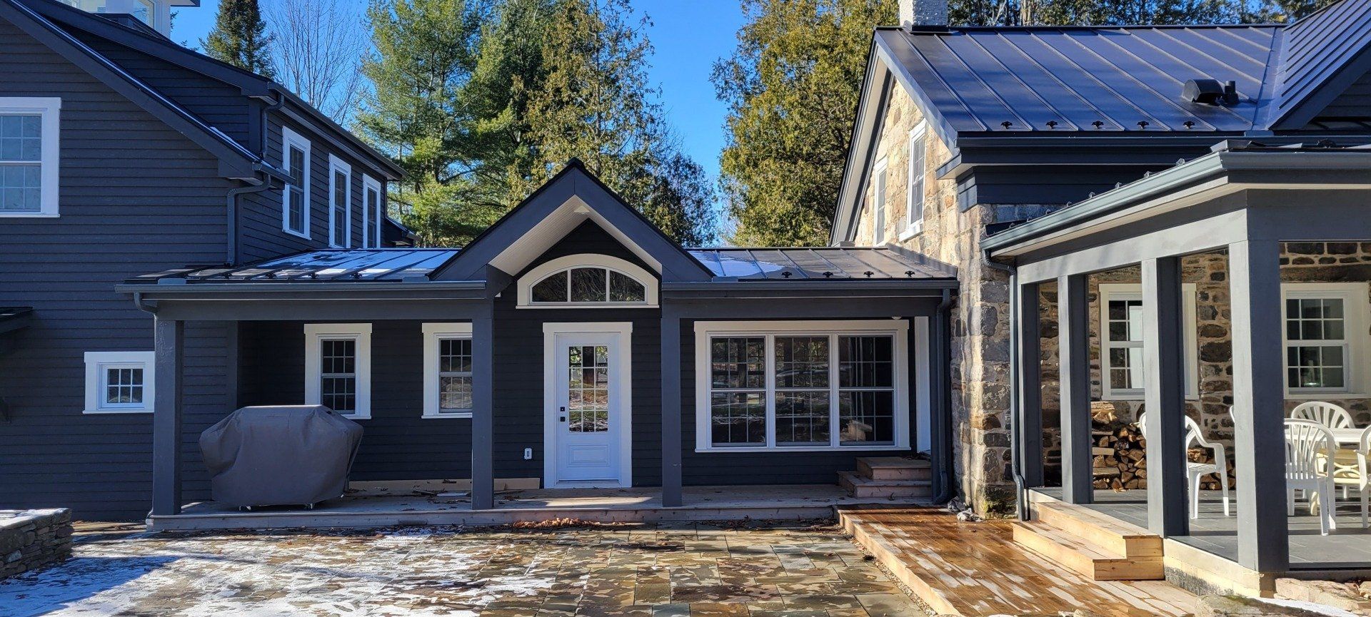 Une maison noire avec une porte blanche et un porche dans la neige.