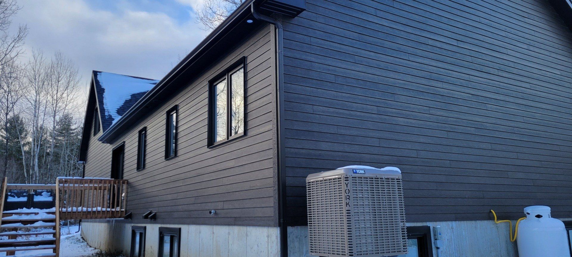 Une grande maison avec beaucoup de fenêtres est assise dans la neige.