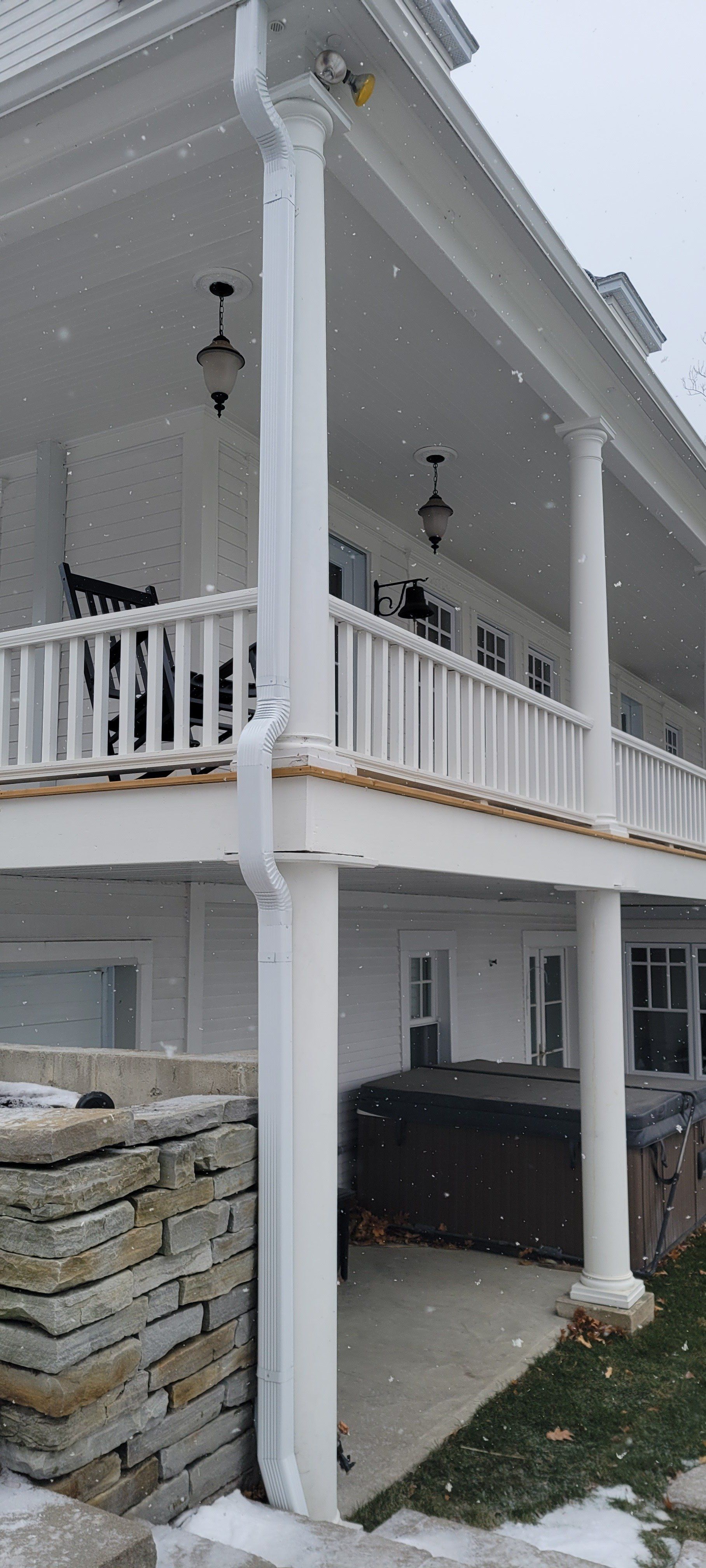 Une grande maison blanche avec un grand porche et un bain à remous en dessous.