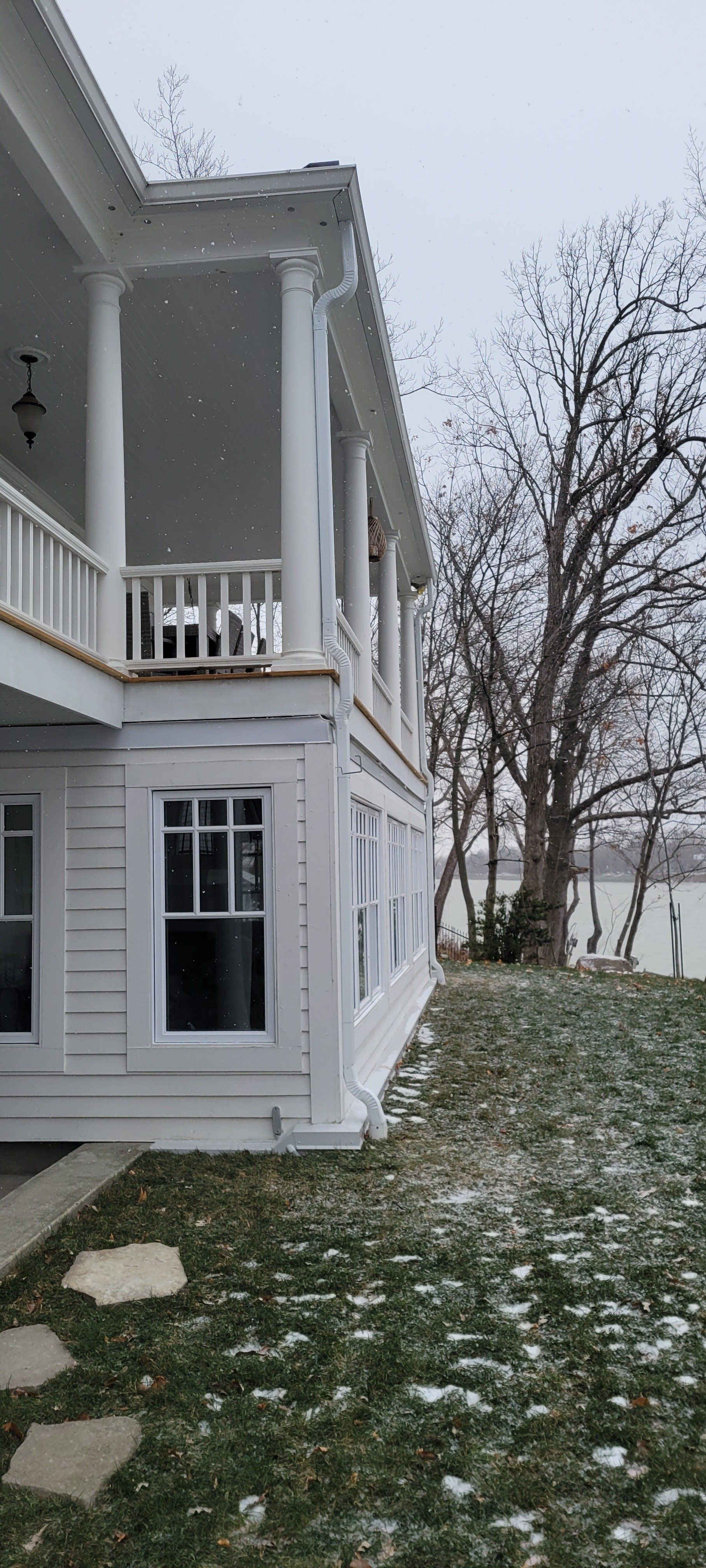 Une grande maison blanche avec un grand porche et beaucoup de fenêtres.